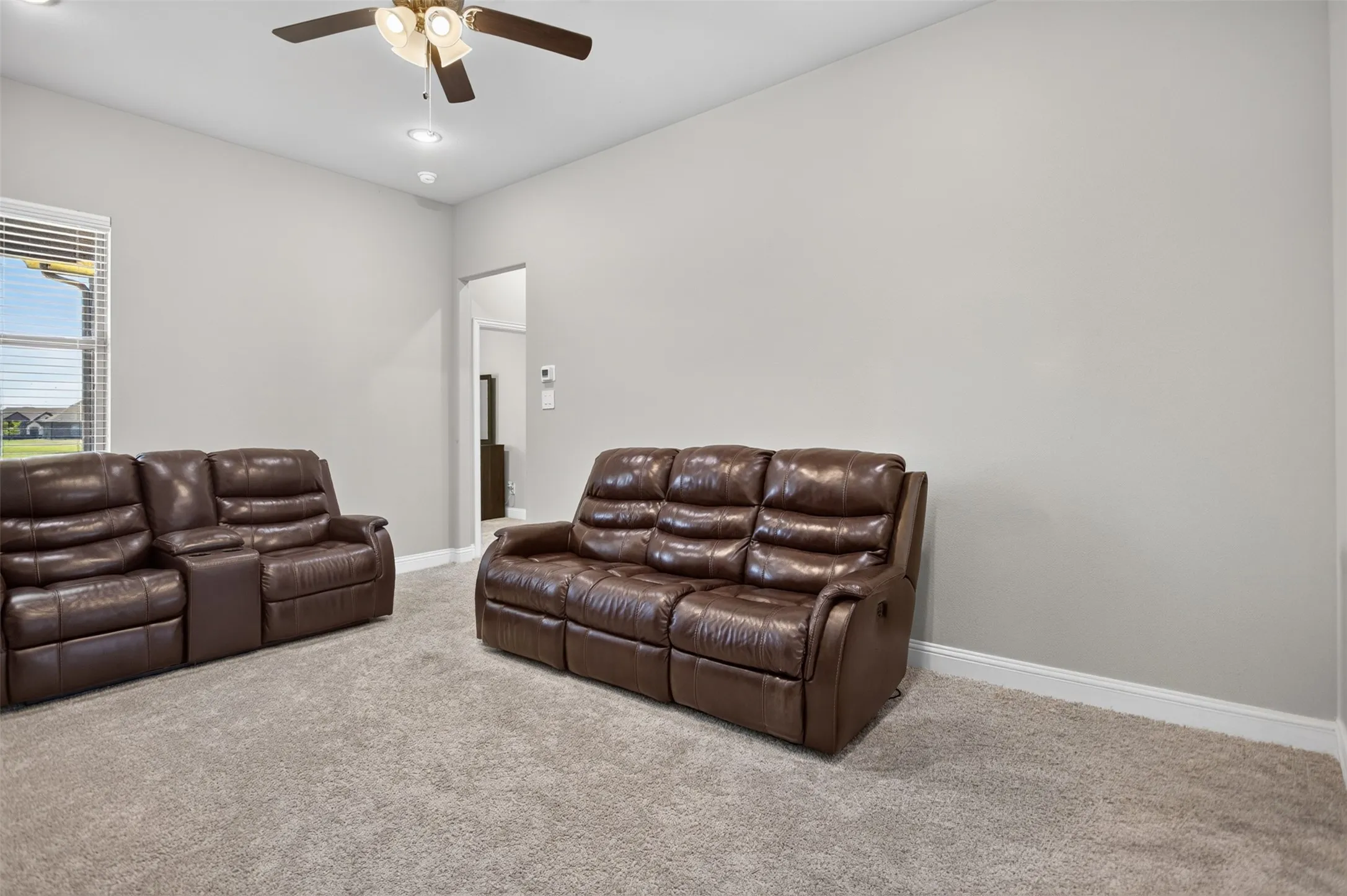 Recessed lighting, ceiling fan fixture, neutral wall color, carpeted flooring, and a large window with blinds