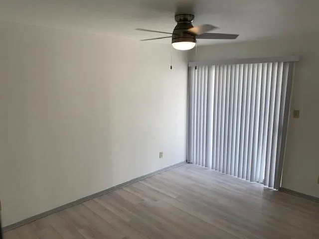 Wood-finish flooring, vertical blinds, and a ceiling fan with integrated lighting