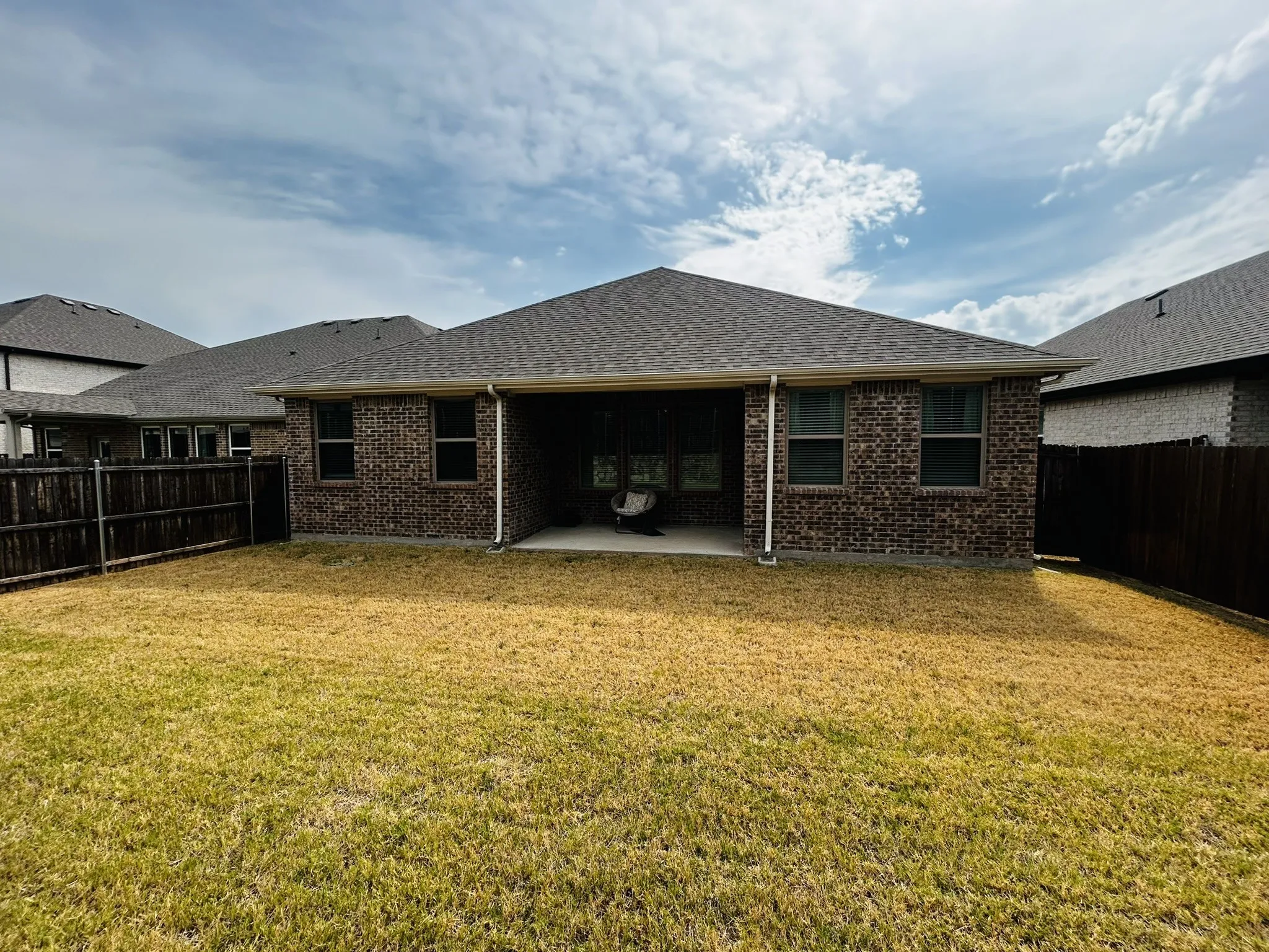 Backyard featuring a covered patio, brick exterior, and a privacy fence
