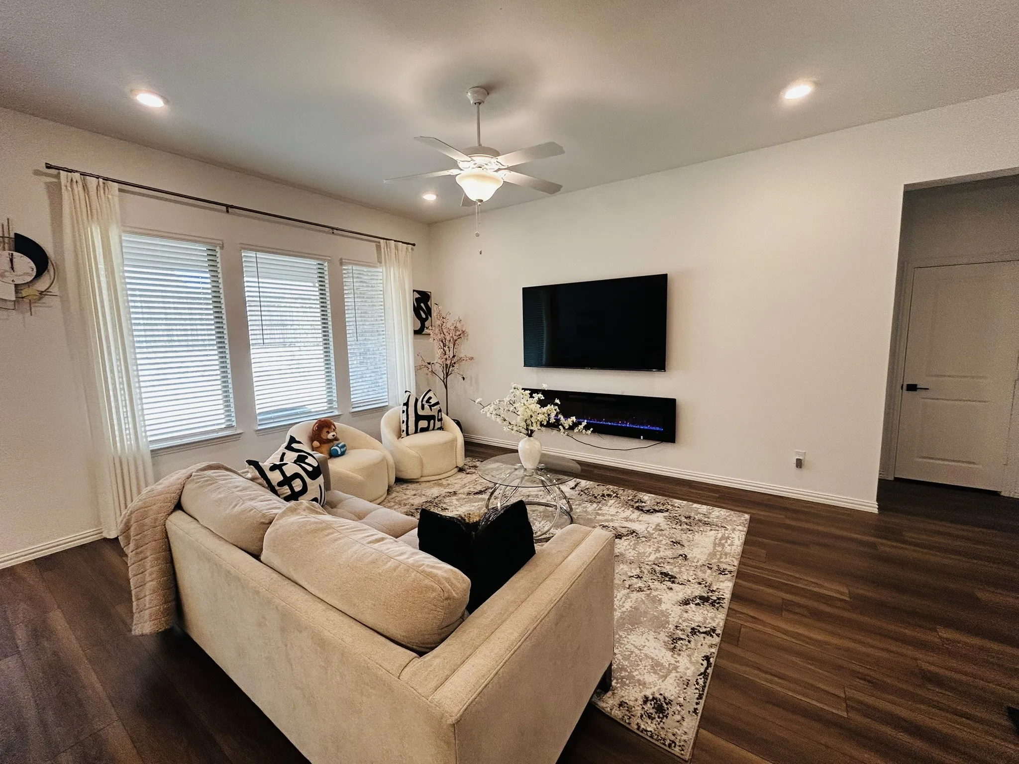 Recessed lighting, wood-finish flooring, ceiling fan, multiple windows with blinds, and a built-in wall-mounted fireplace