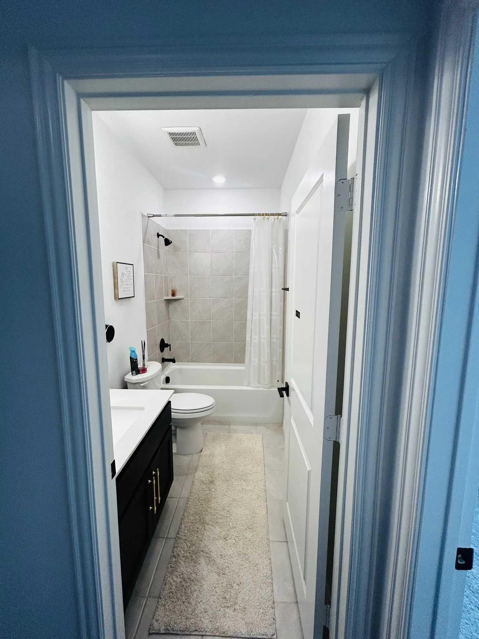 Full bathroom with a dark wood-finish vanity, integrated sink, and matte black hardware