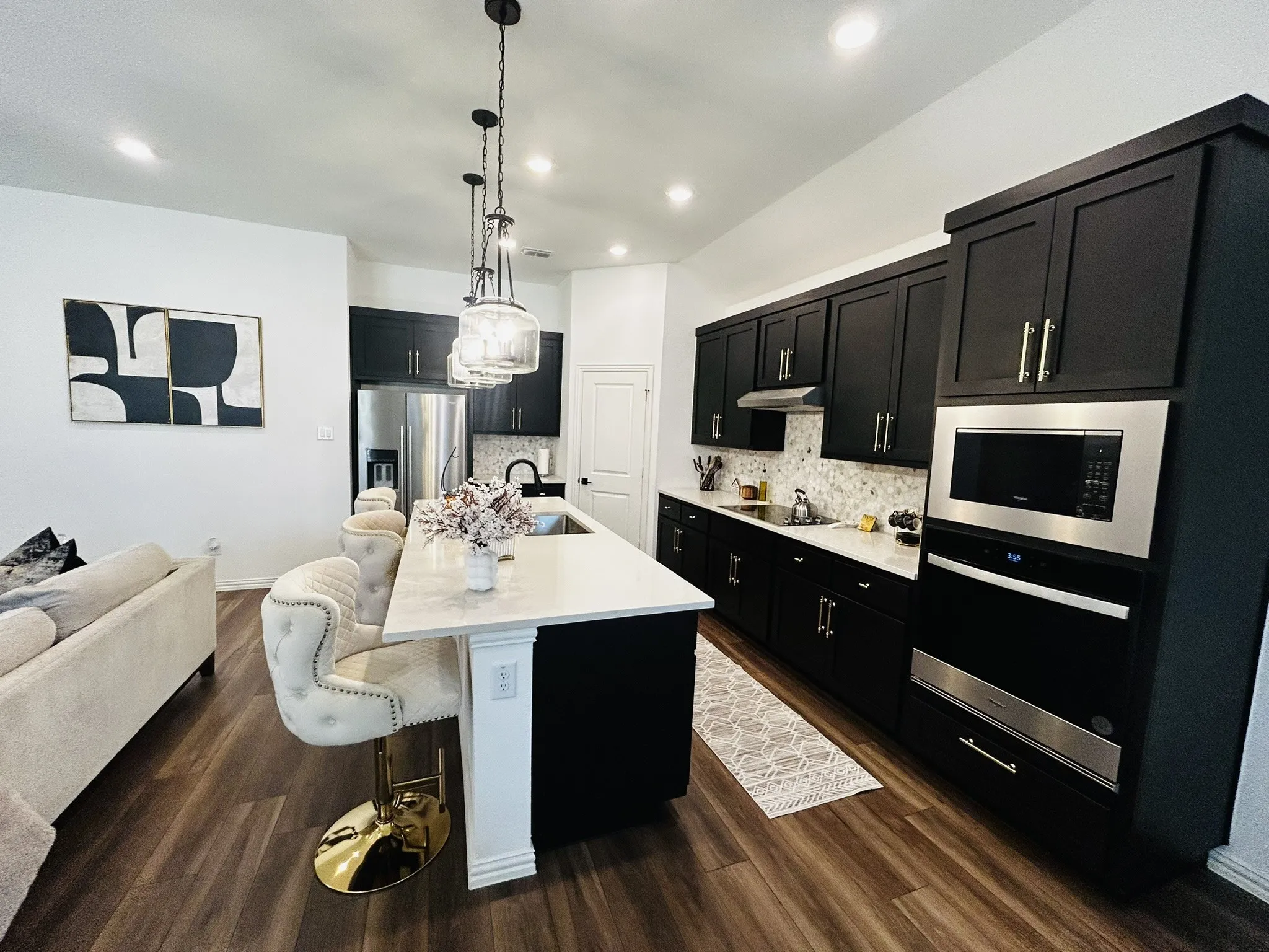 Kitchen featuring wood-finish flooring, dark cabinetry, light countertops, and integrated stainless steel appliances