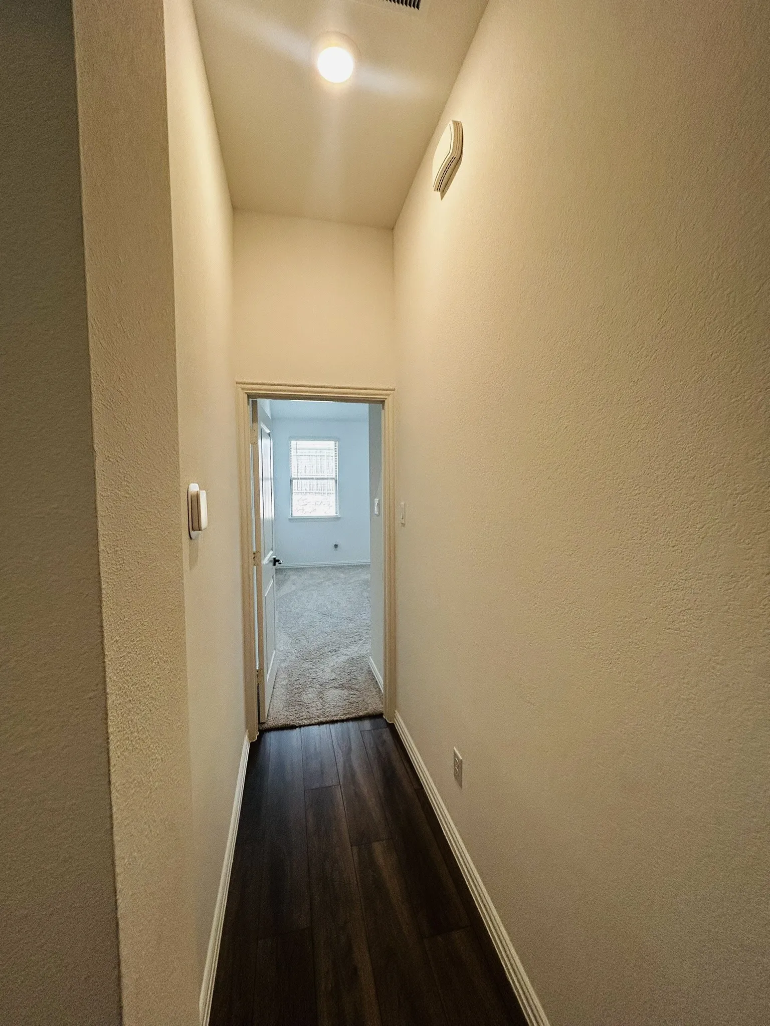 Wood-finish flooring leading to a room with carpet
