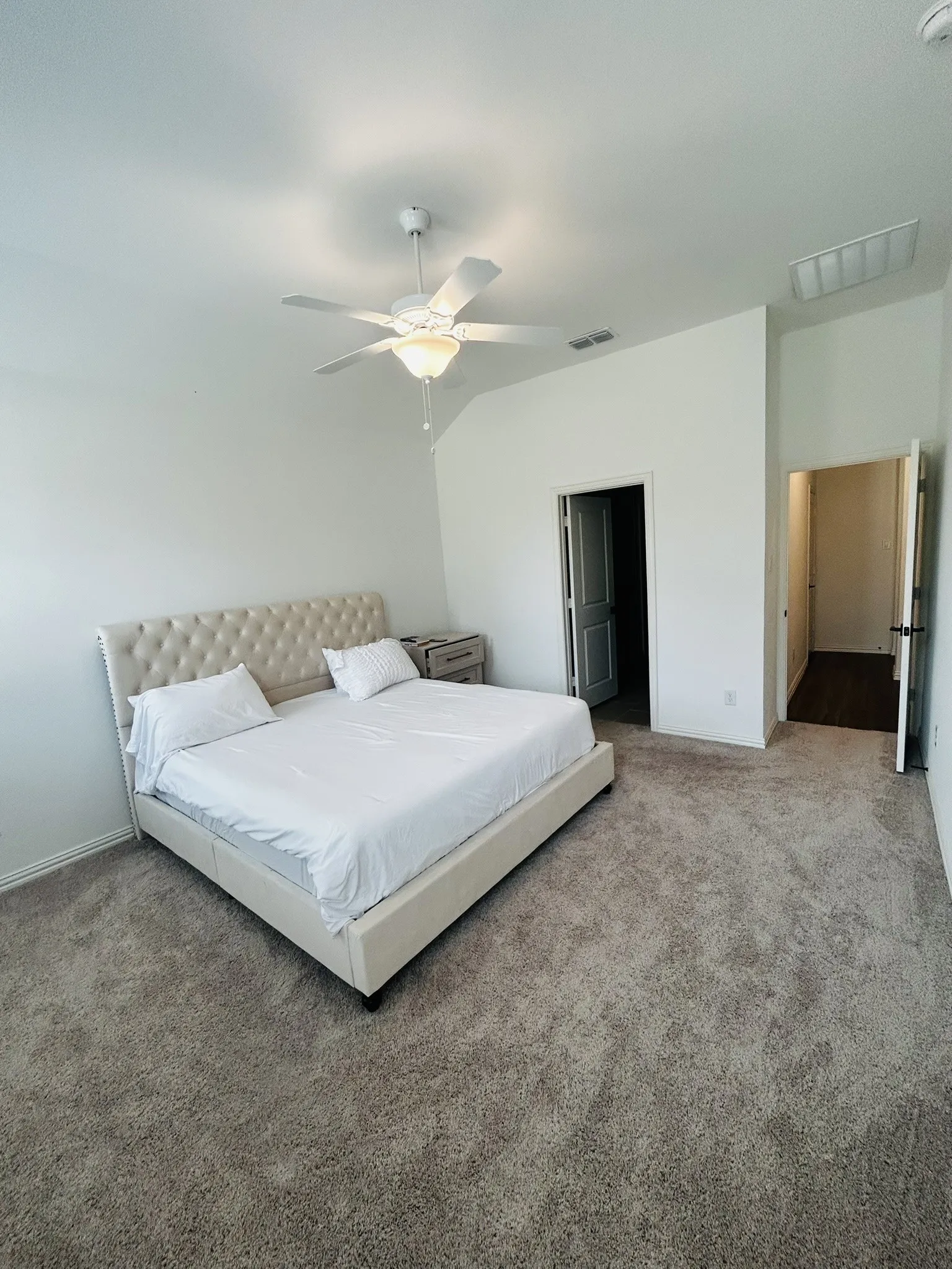 Recessed ceiling lighting illuminates a hallway with wood-finish flooring and white walls