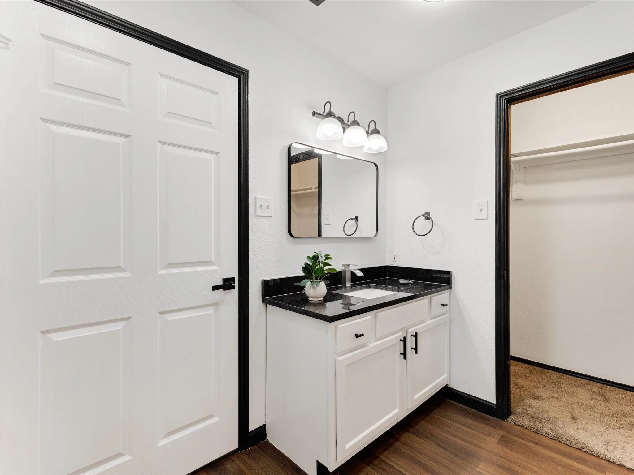 White vanity with black hardware, black countertop, and undermount sink