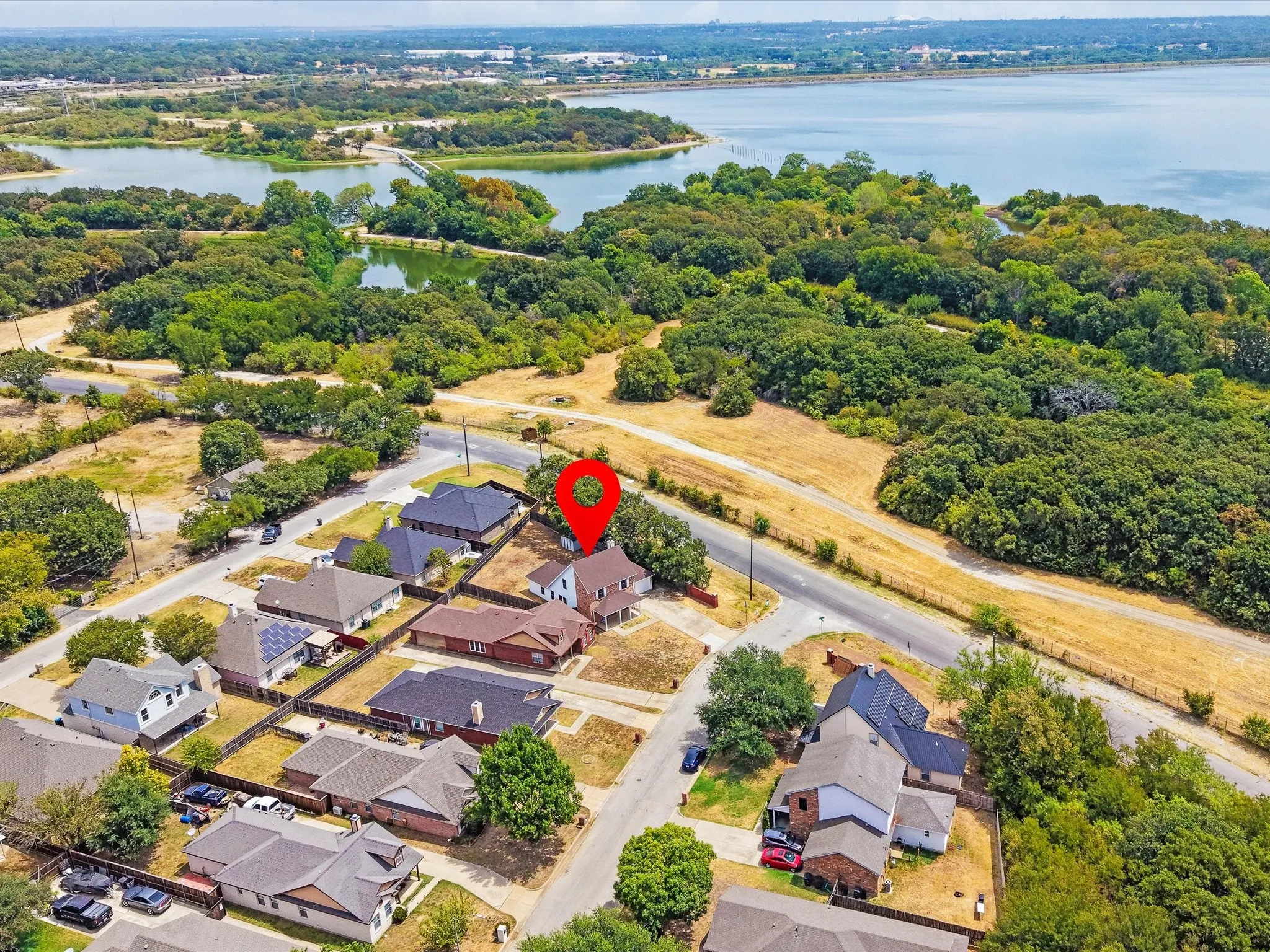 Aerial perspective showcasing a residential neighborhood bordering a substantial body of water and dense tree lines
