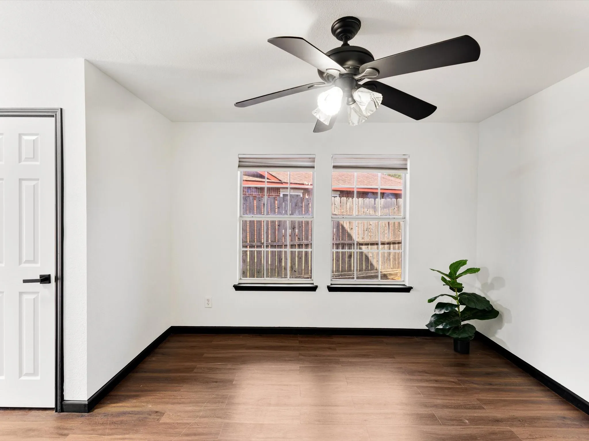 Wood-finish flooring, white walls, and a ceiling fan with integrated lighting