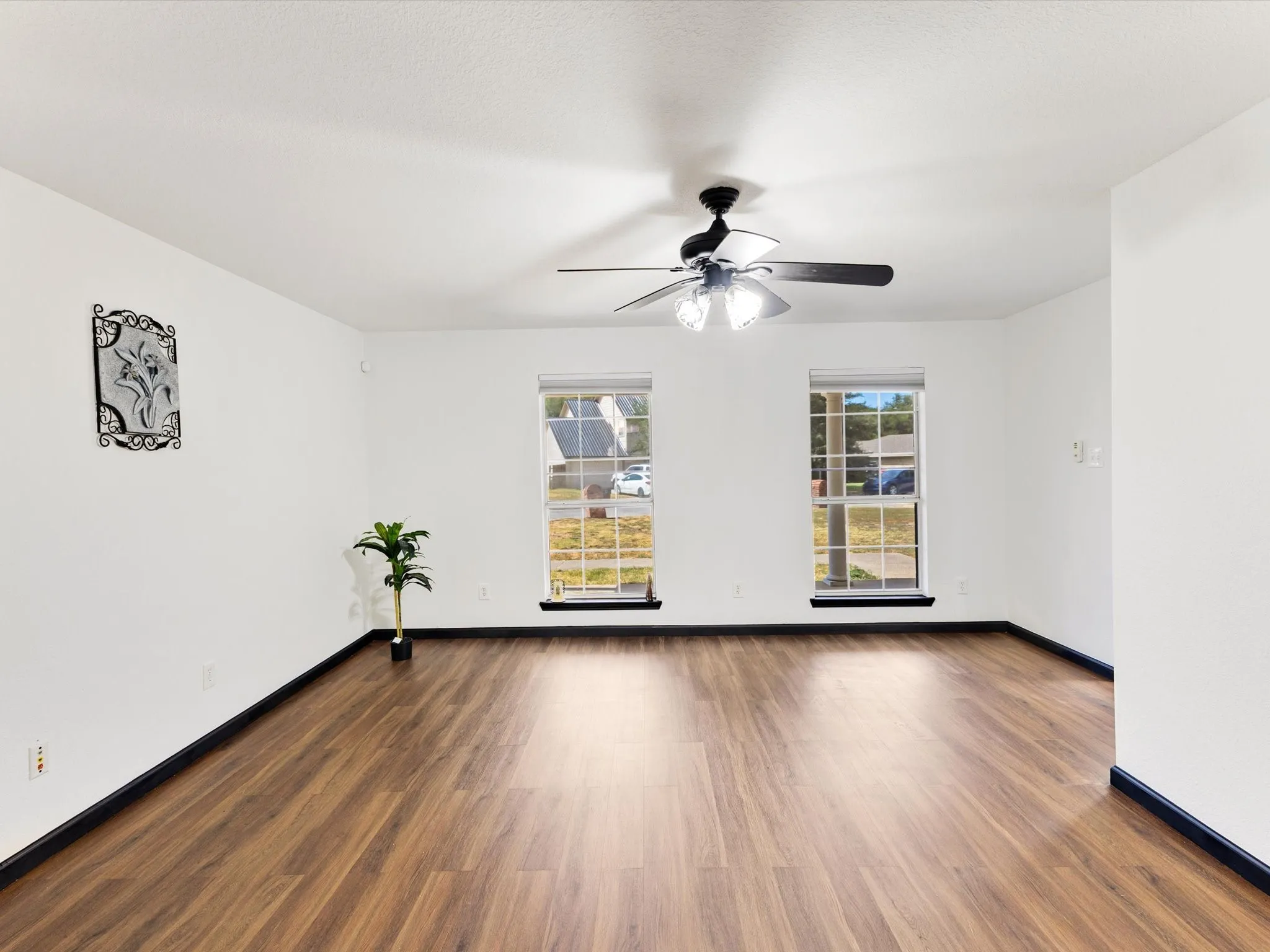 Spacious interior featuring wood-finish flooring, white walls, and a ceiling fan