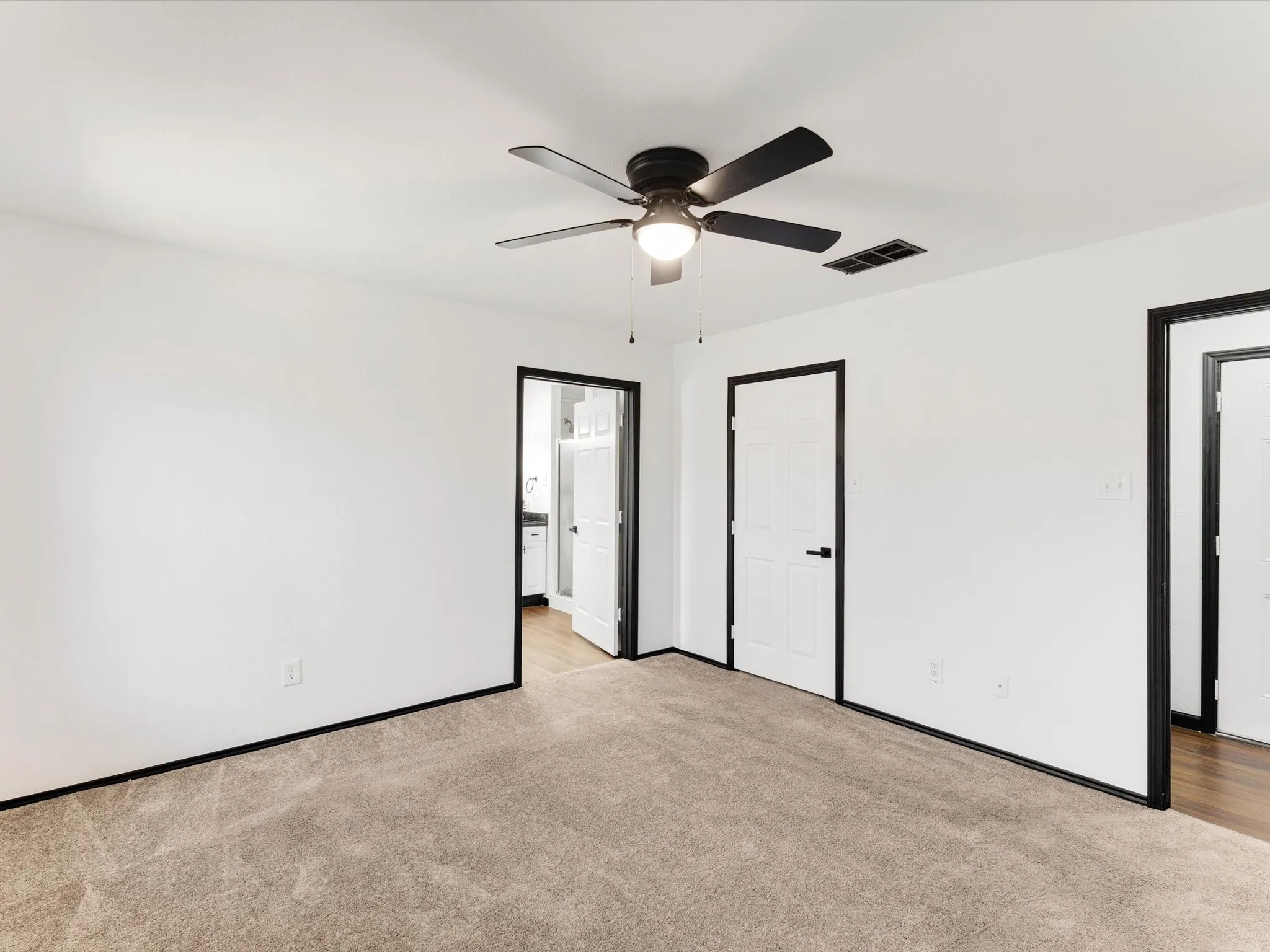 Plush carpet flooring, white walls, black trim, and a ceiling fan with integrated lighting