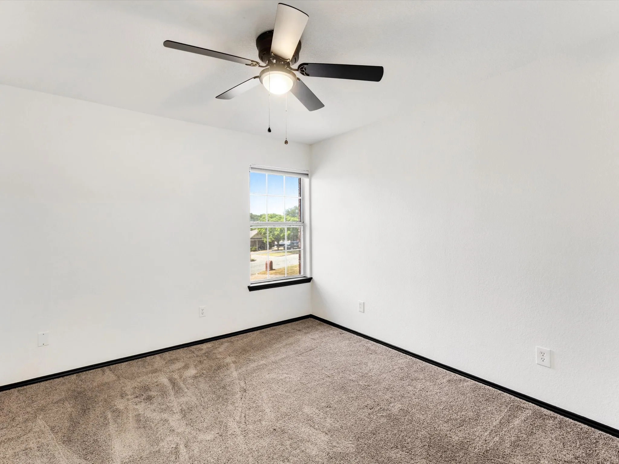 Neutral wall finishes, recessed window, dark window trim, dark ceiling fan with integrated lighting, and carpet flooring