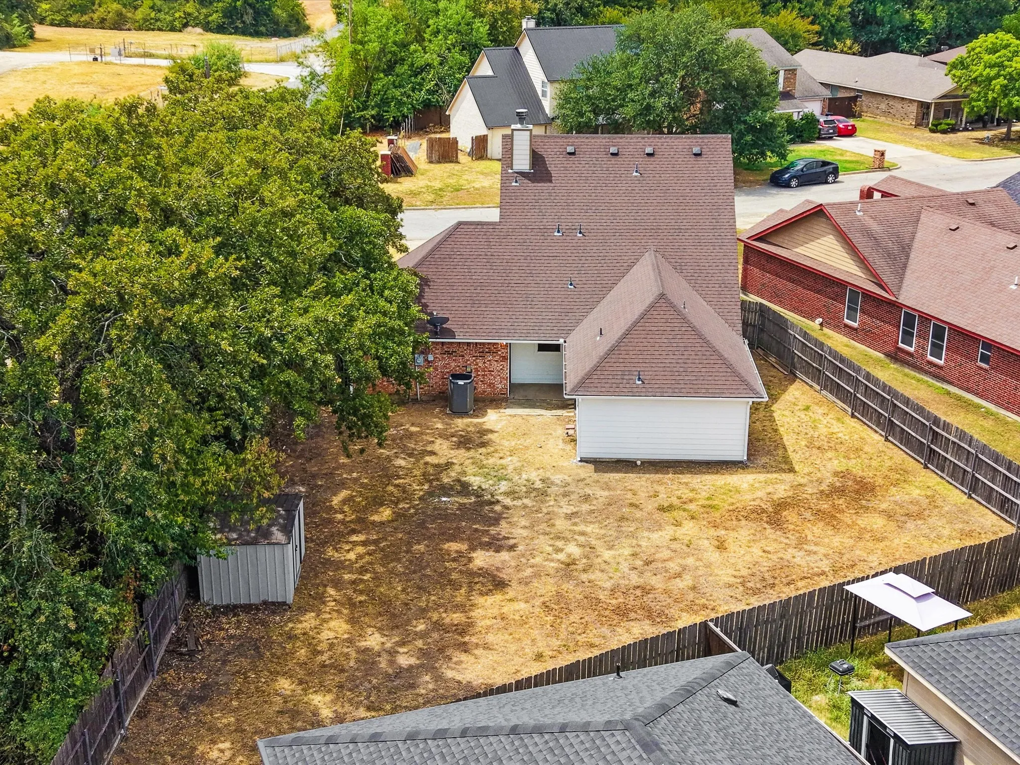 Fenced backyard featuring a storage shed and mature trees