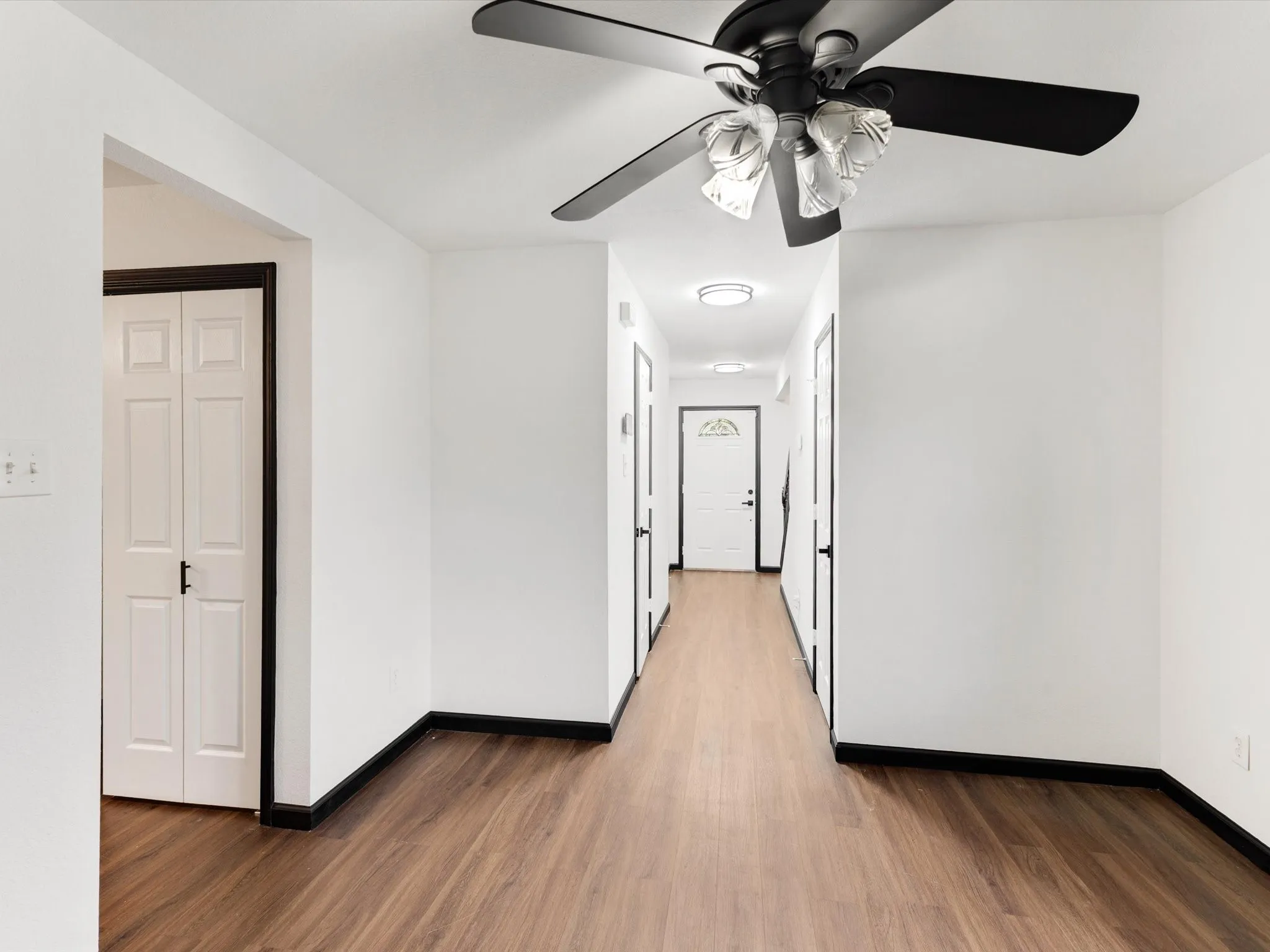 Wood-finish flooring throughout, white walls, and dark trim