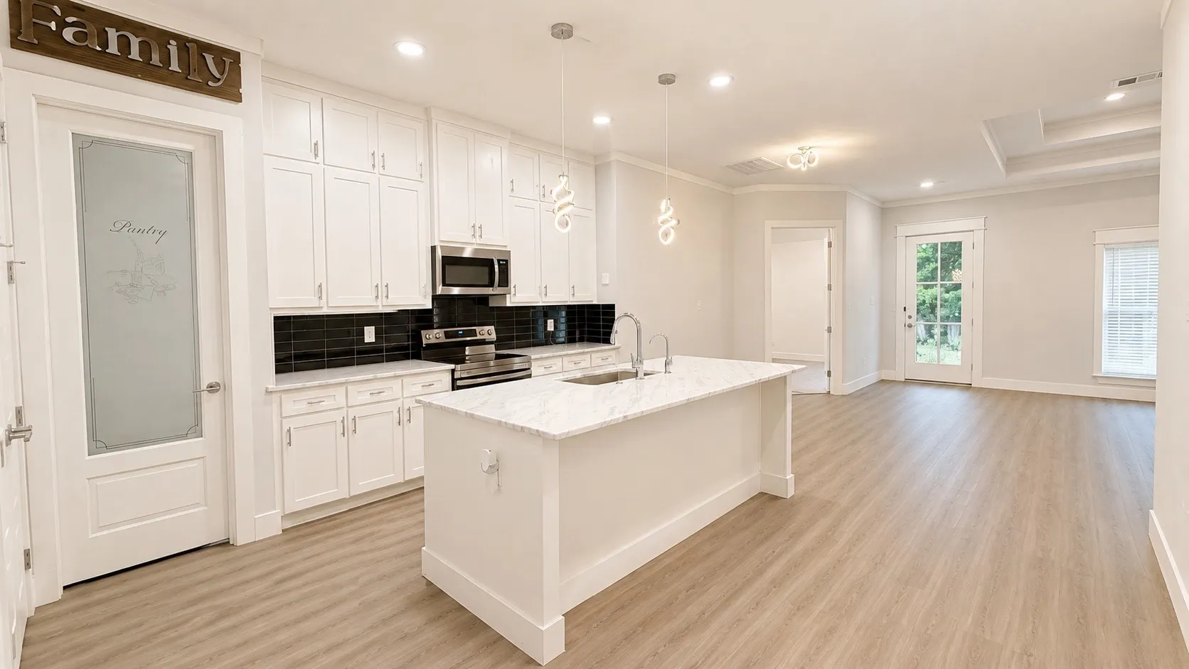 Modern kitchen featuring white cabinetry, stainless steel appliances, and a central island with a sink