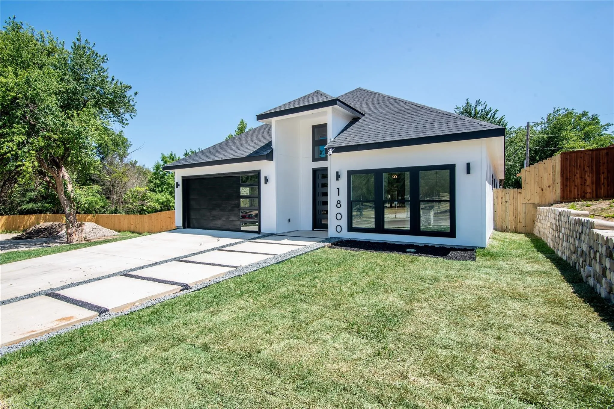 White stucco exterior with black trim accents and a dark shingle roof