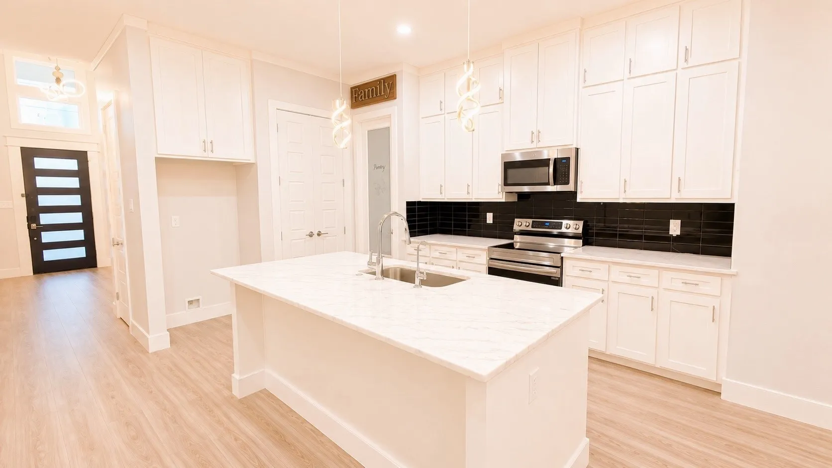 Kitchen featuring a large island with sink, stainless steel appliances, extensive white cabinetry, and wood-finish flooring