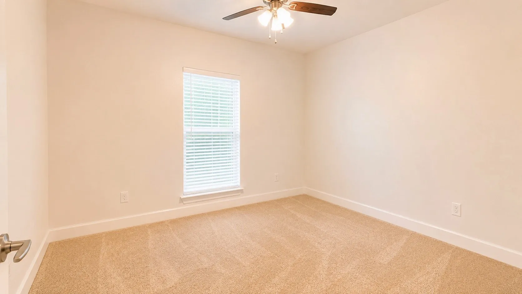 Neutral toned walls, carpet flooring, a window with blinds, and a ceiling fan with integrated lighting