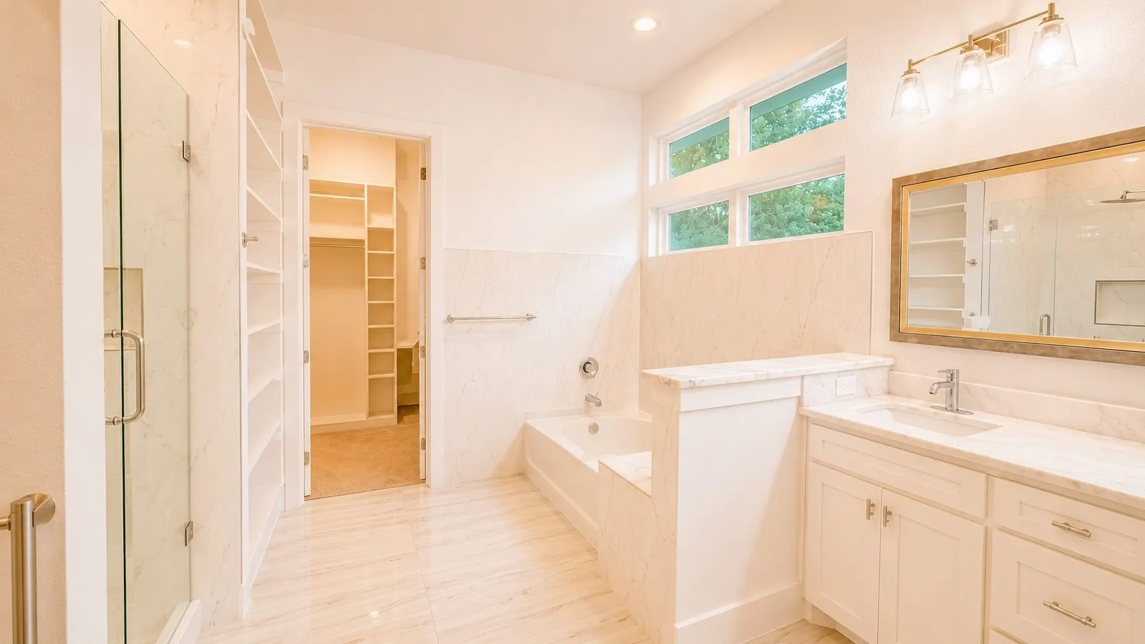 White tile flooring, built-in shelving, glass-enclosed shower, built-in bathtub, and a vanity with an undermount sink