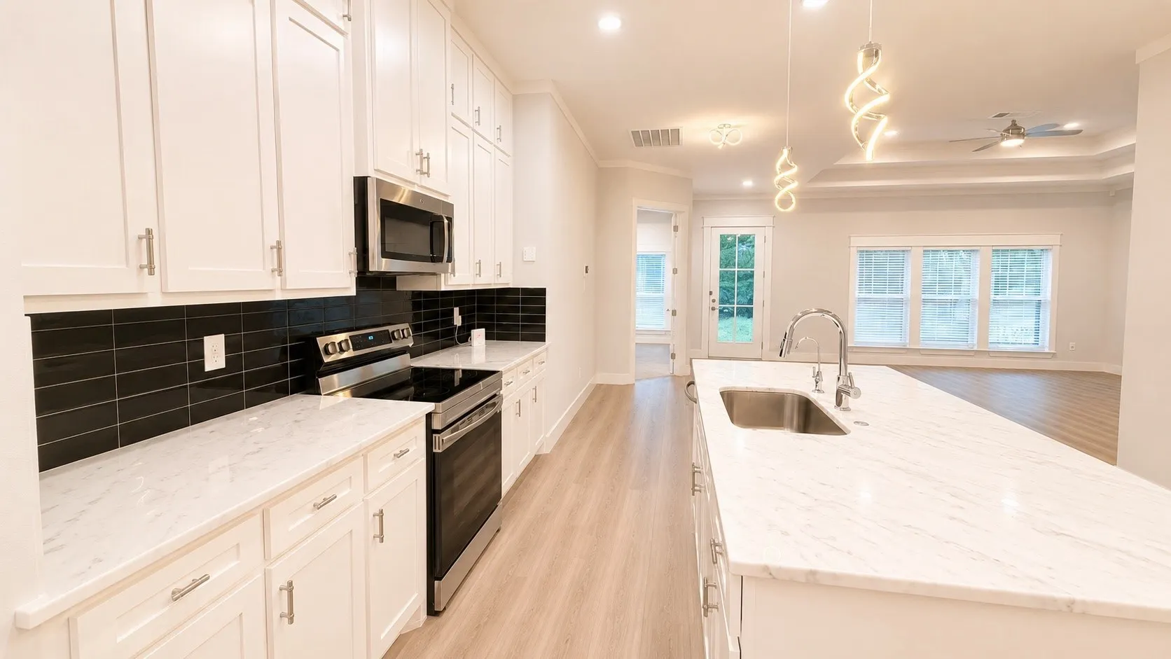 Kitchen featuring white cabinetry, light-toned countertops, a black subway tile backsplash, and stainless steel appliances