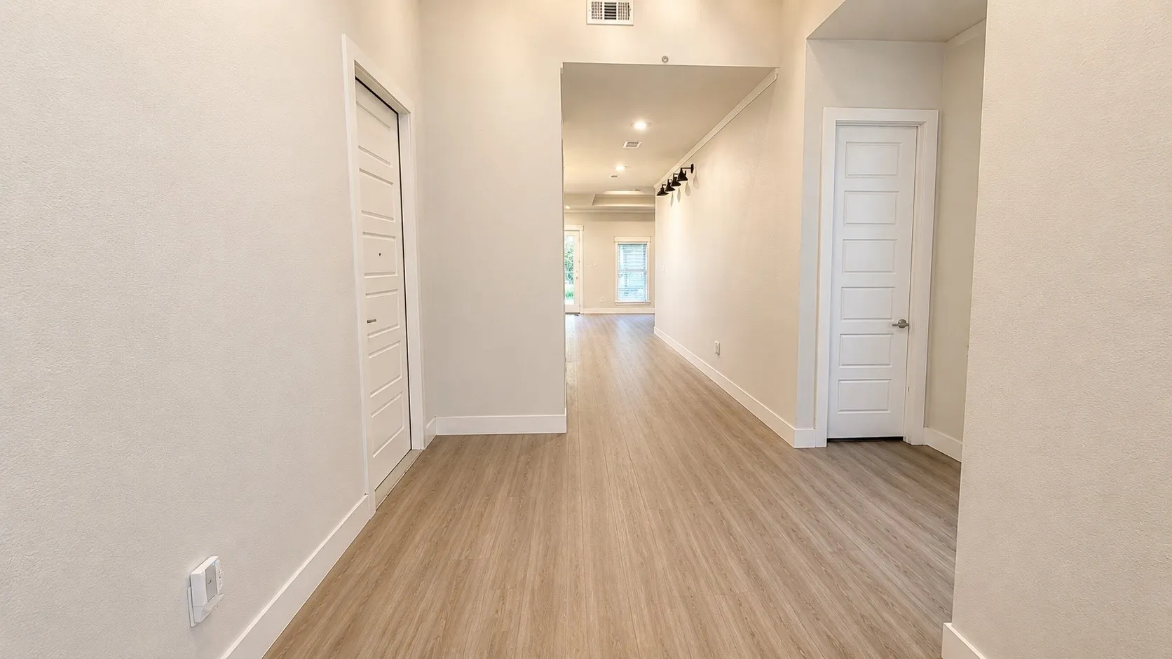Wood-finish flooring throughout, white paneled doors, and recessed ceiling lighting
