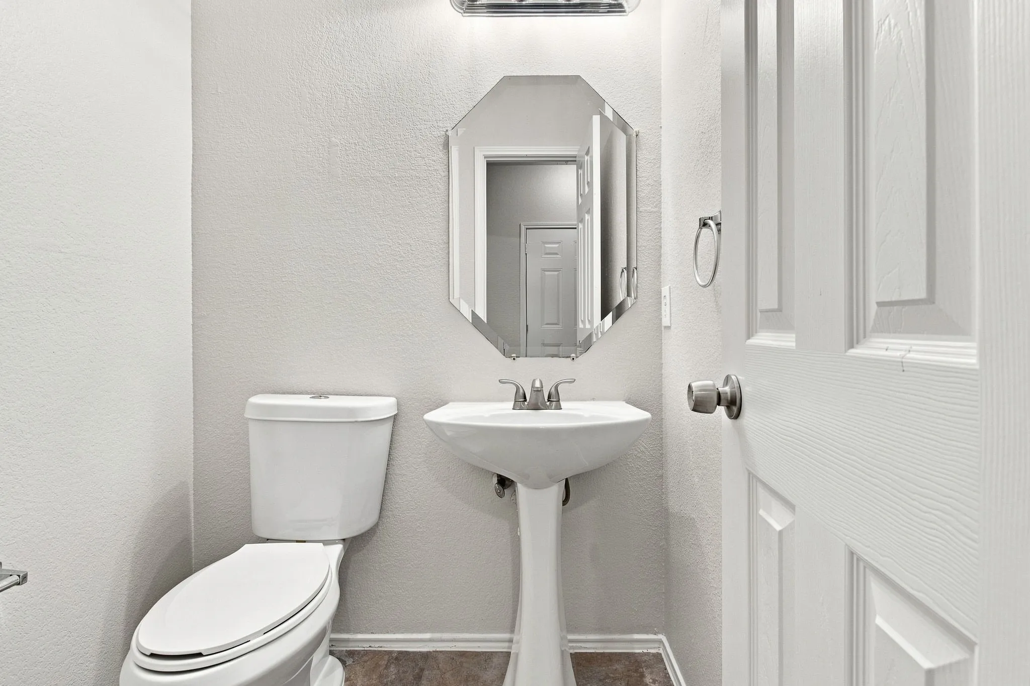 Pedestal sink with chrome faucet, octagonal mirror, and light fixture