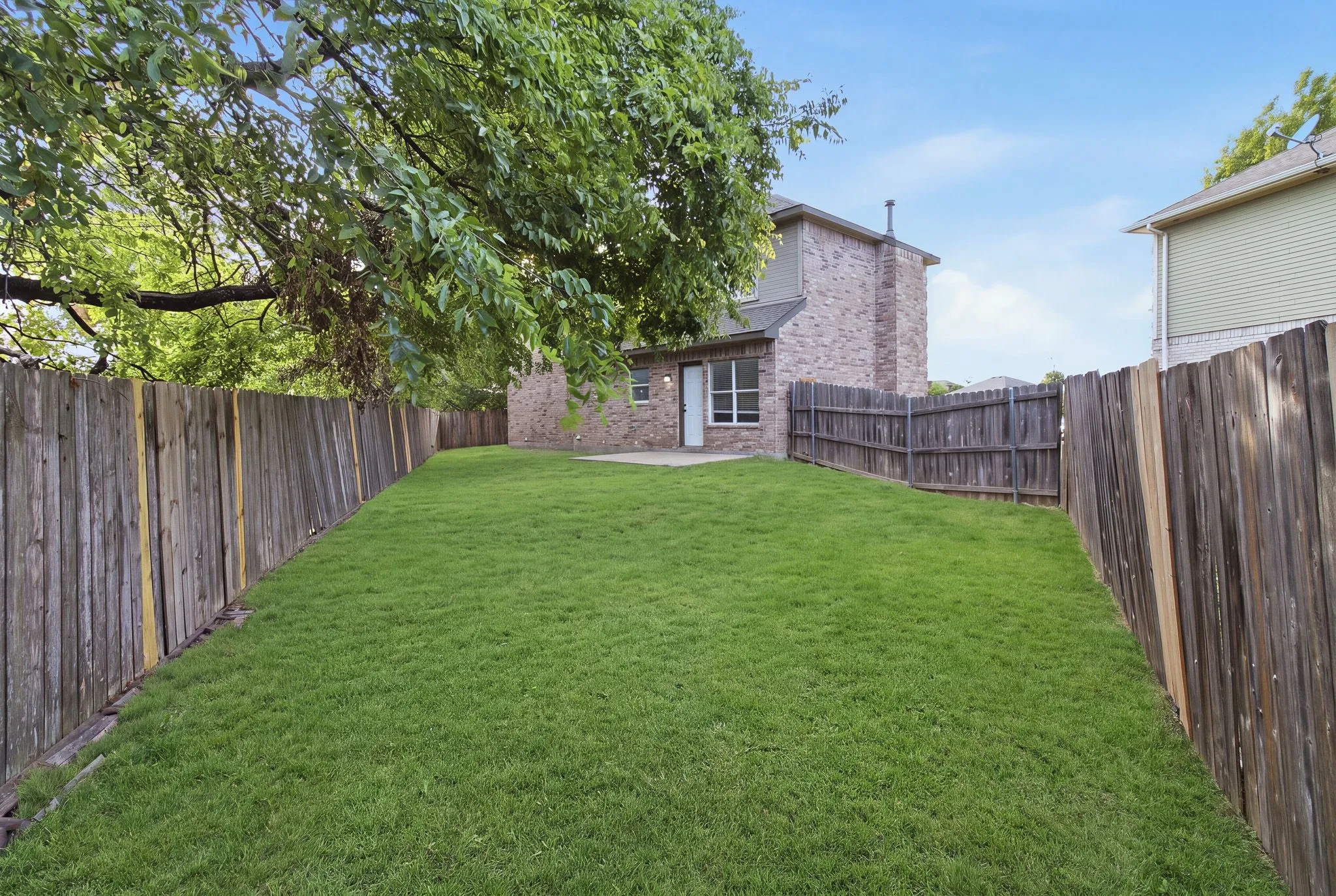 Expansive grassy yard enclosed by wood fencing