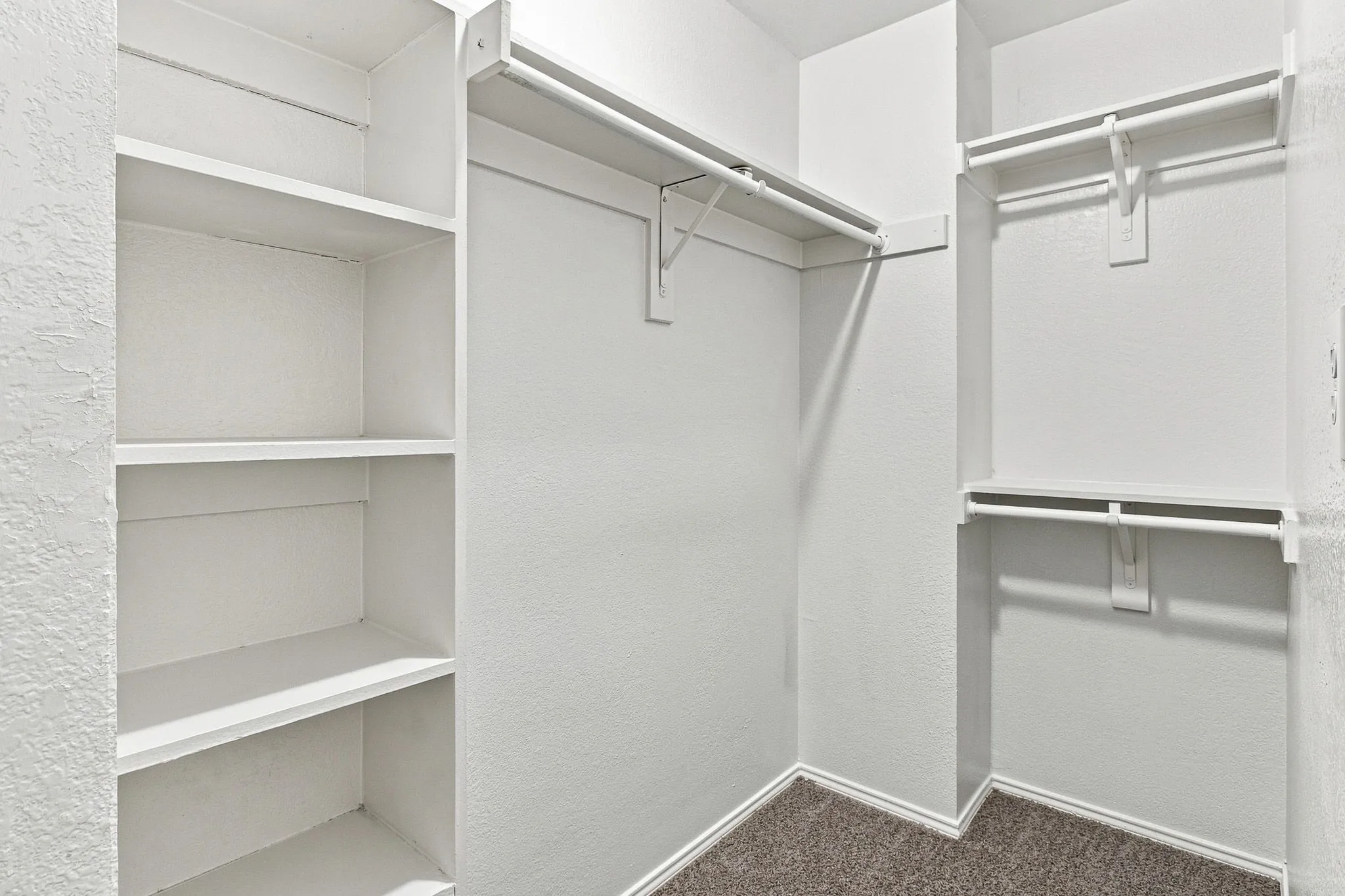 Custom built-in shelving, multiple hanging rods, and textured wall finish