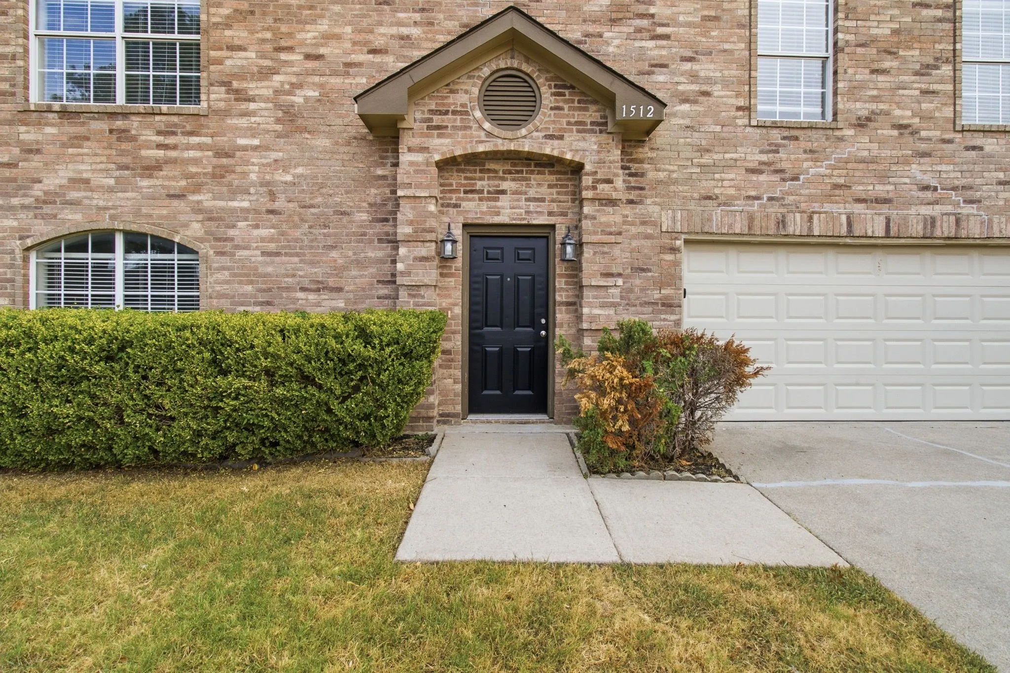 Brick exterior with a prominent entry, an arched window, and an attached garage