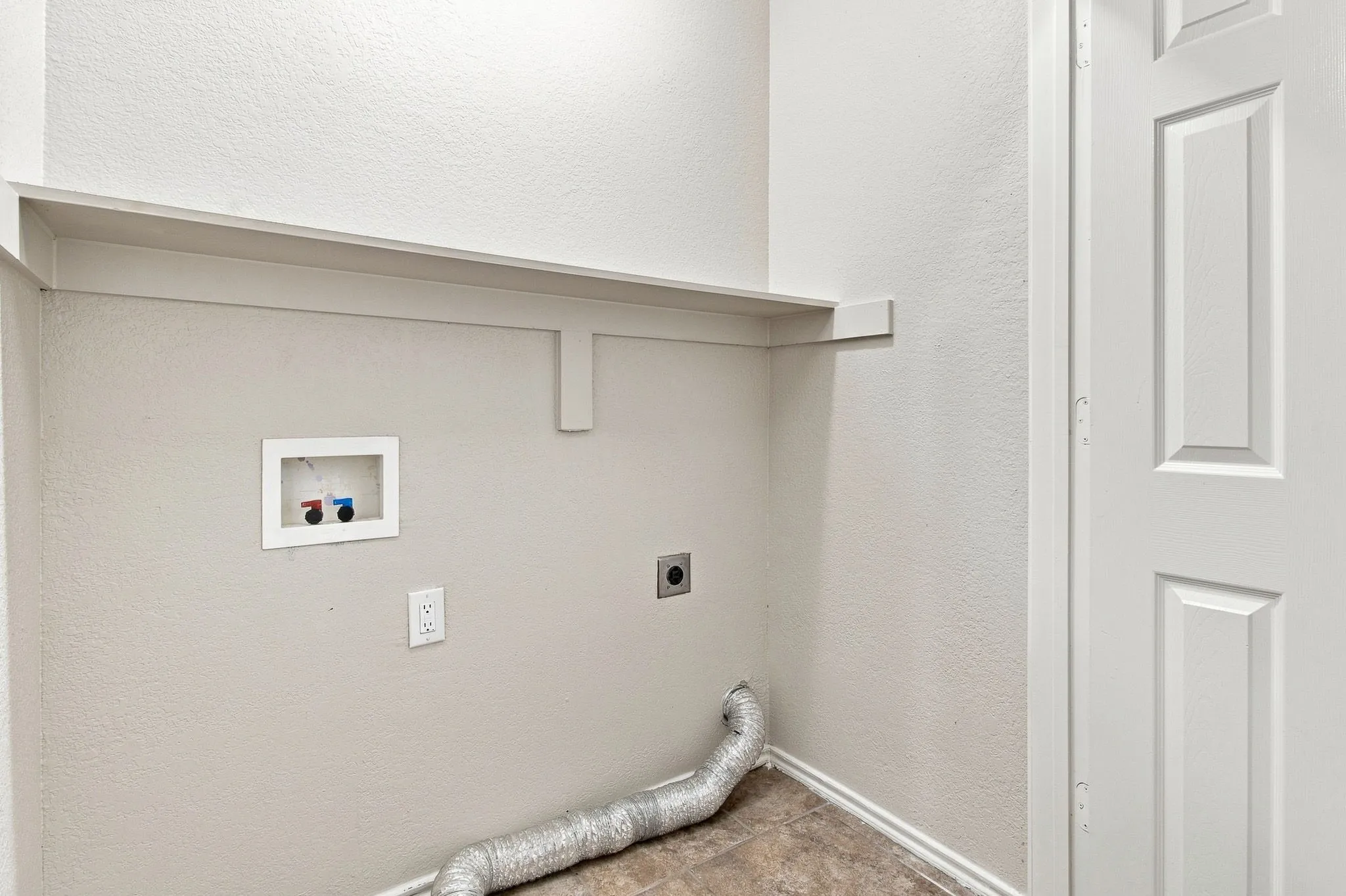 Utility area featuring a built-in shelf, neutral wall tones, and panel door