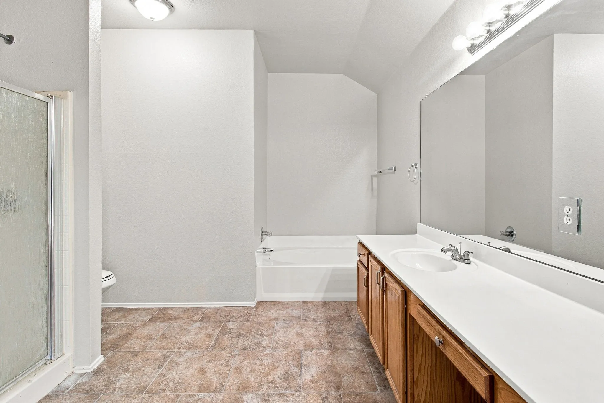 Bathroom featuring a shower enclosure, a bathtub, a vanity with a single basin, a mirror, and tiled flooring