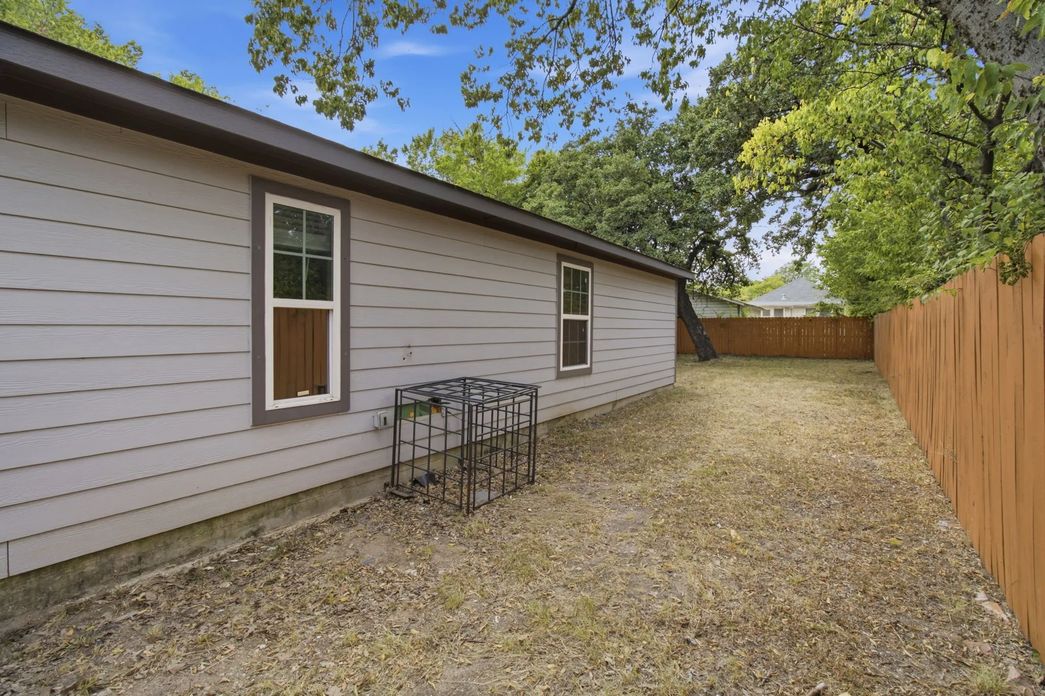 Exterior wall with light gray siding, white-framed windows with dark trim, and a brown roofline