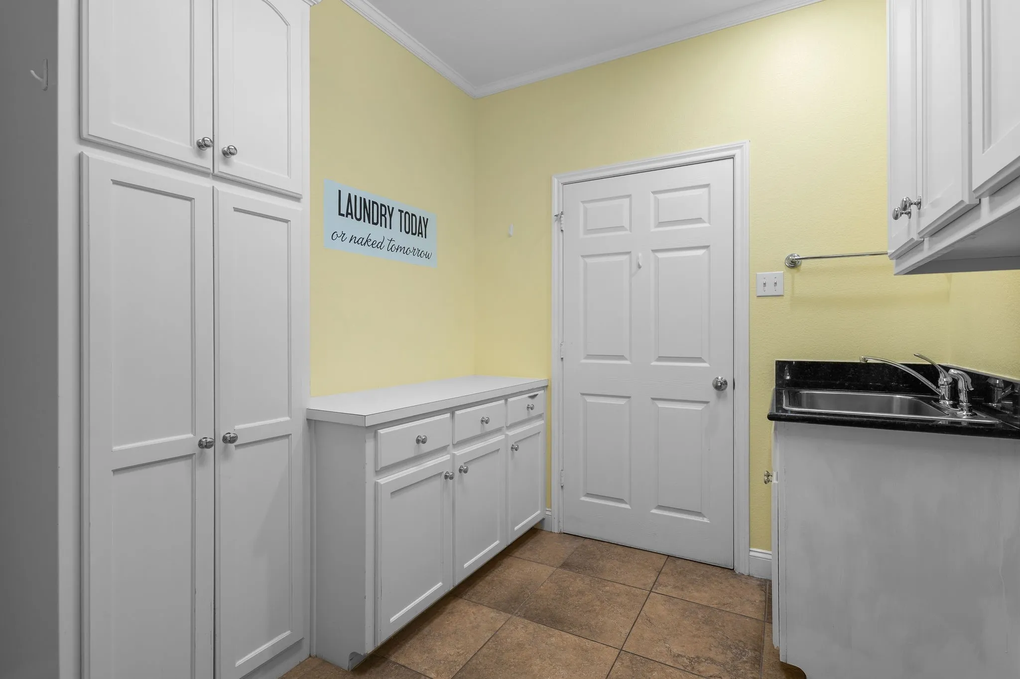Built-in cabinetry with ample storage, integrated sink, stone countertop, tiled flooring, and a solid panel door