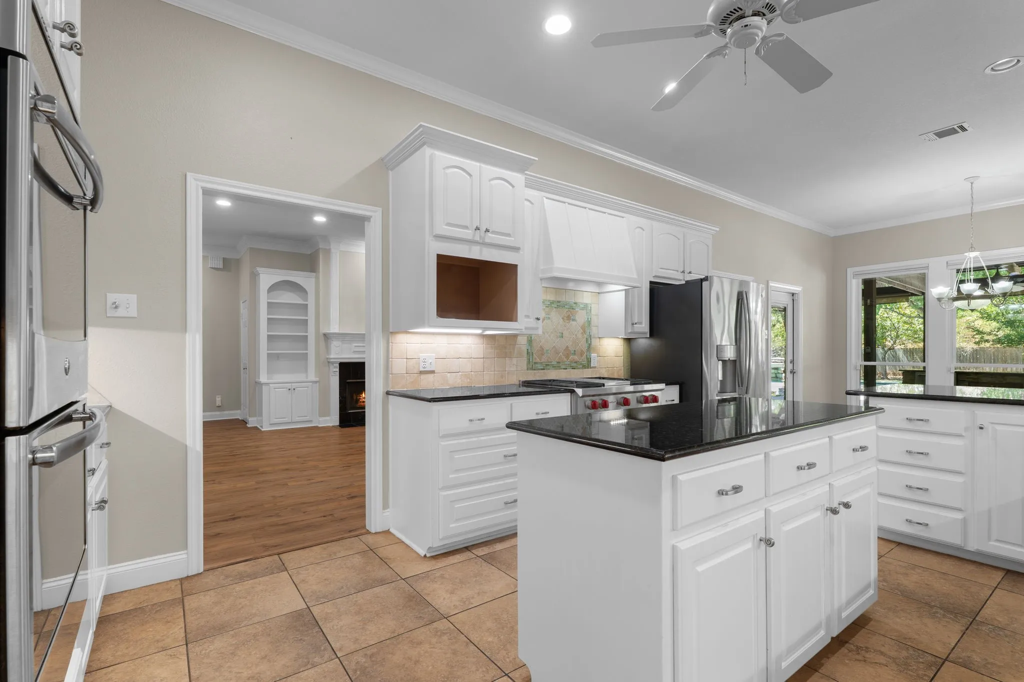 White cabinetry with dark countertops, a central island, stainless steel appliances, and tile flooring