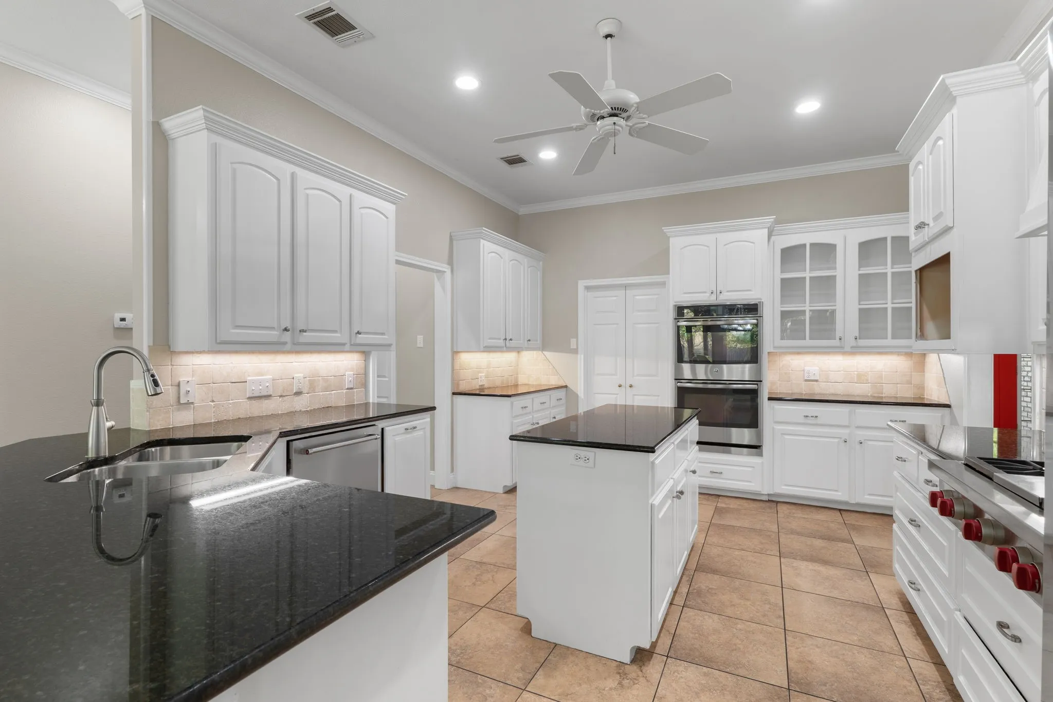 Kitchen with white cabinetry, black stone countertops, stainless steel appliances, a center island, and tile flooring