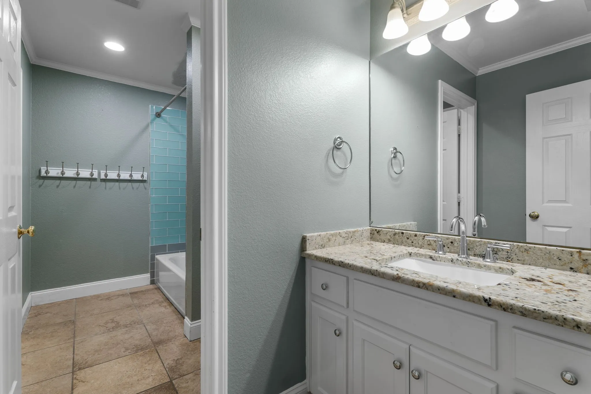 Bathroom featuring a vanity with a light-toned countertop, integrated sink, and white cabinetry