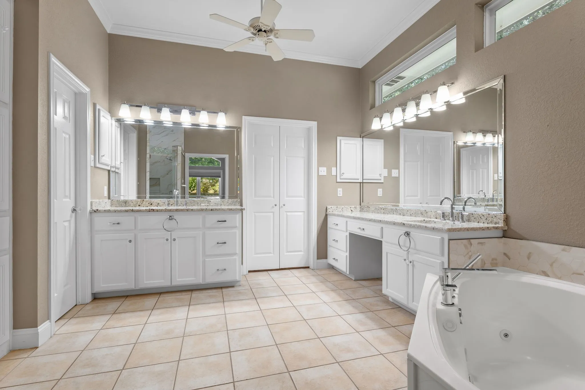 Dual vanity with white cabinetry, granite countertops, tile flooring, and a built-in jetted tub