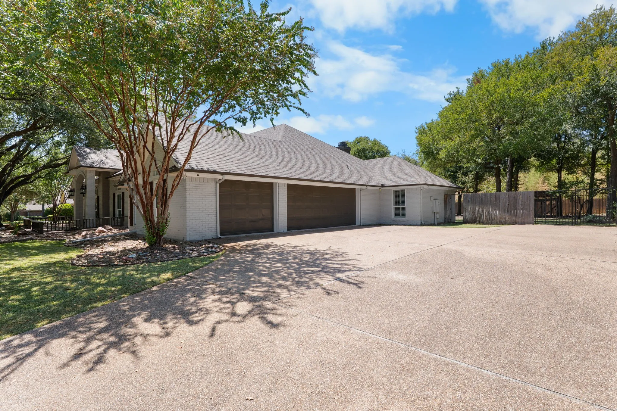 Stucco exterior with a shingle roof, two-car garage, and an expansive concrete driveway