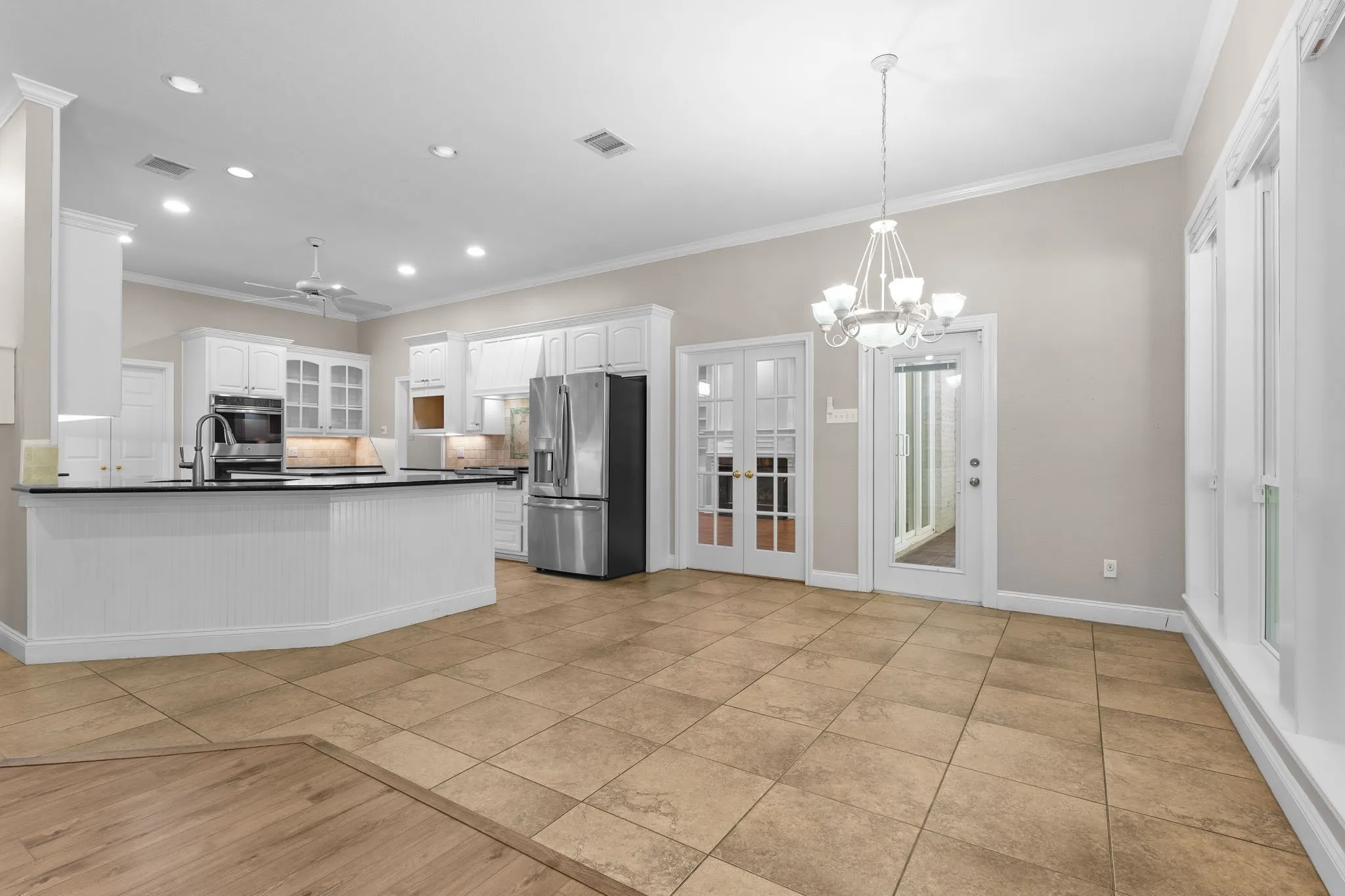 Kitchen featuring white cabinetry, stainless steel appliances, dark countertops, and a peninsula with beadboard detailing