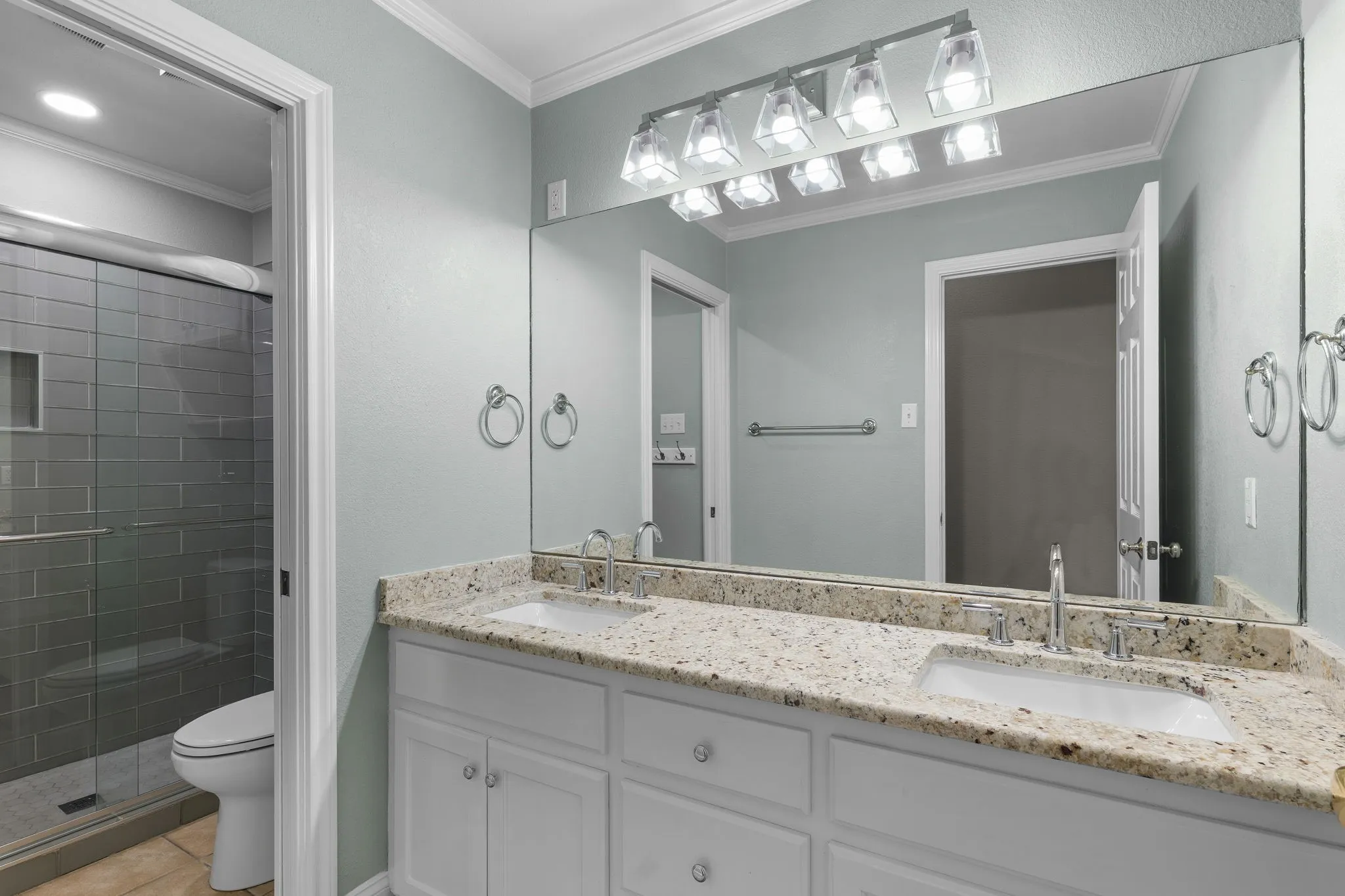Dual vanity with undermount sinks, stone countertops, and chrome fixtures