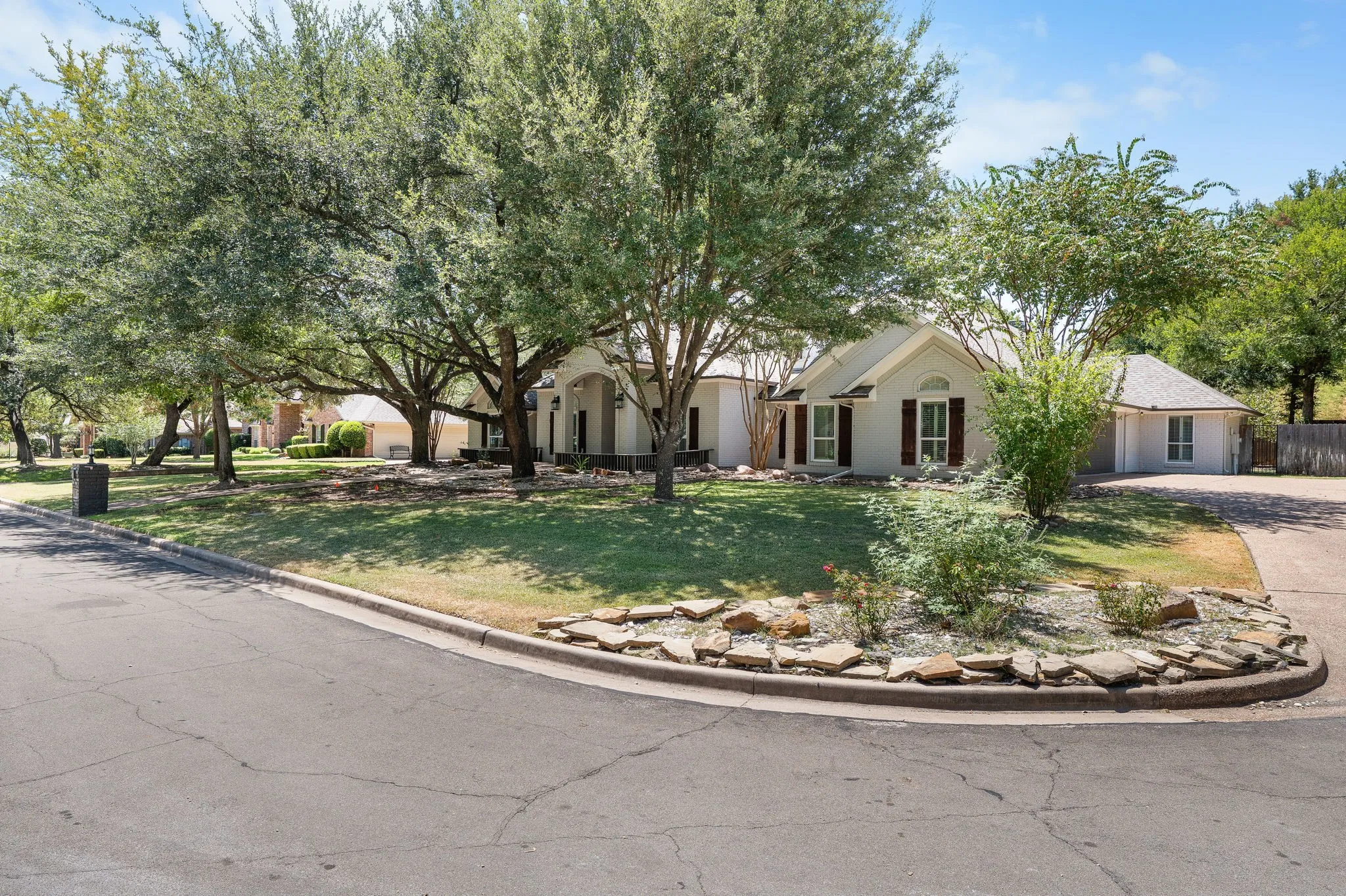 Single-story residence with a light-colored exterior, an attached garage, and a peaked roofline