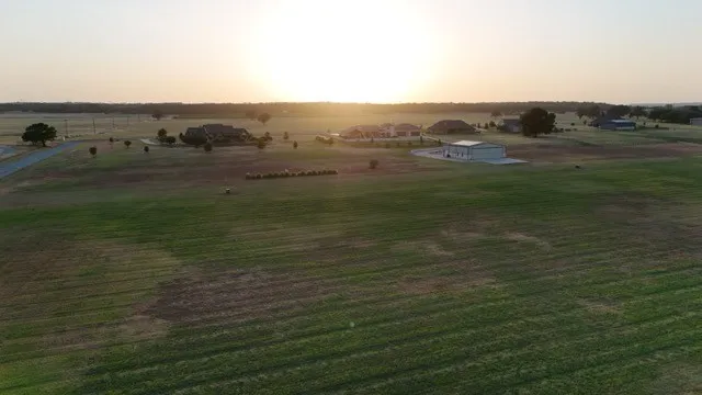 Expansive open land with distant residential structures and mature trees