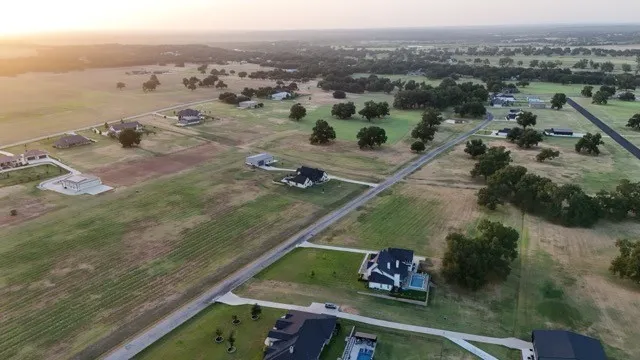 Expansive property featuring scattered mature trees, paved roads, and multiple residential structures