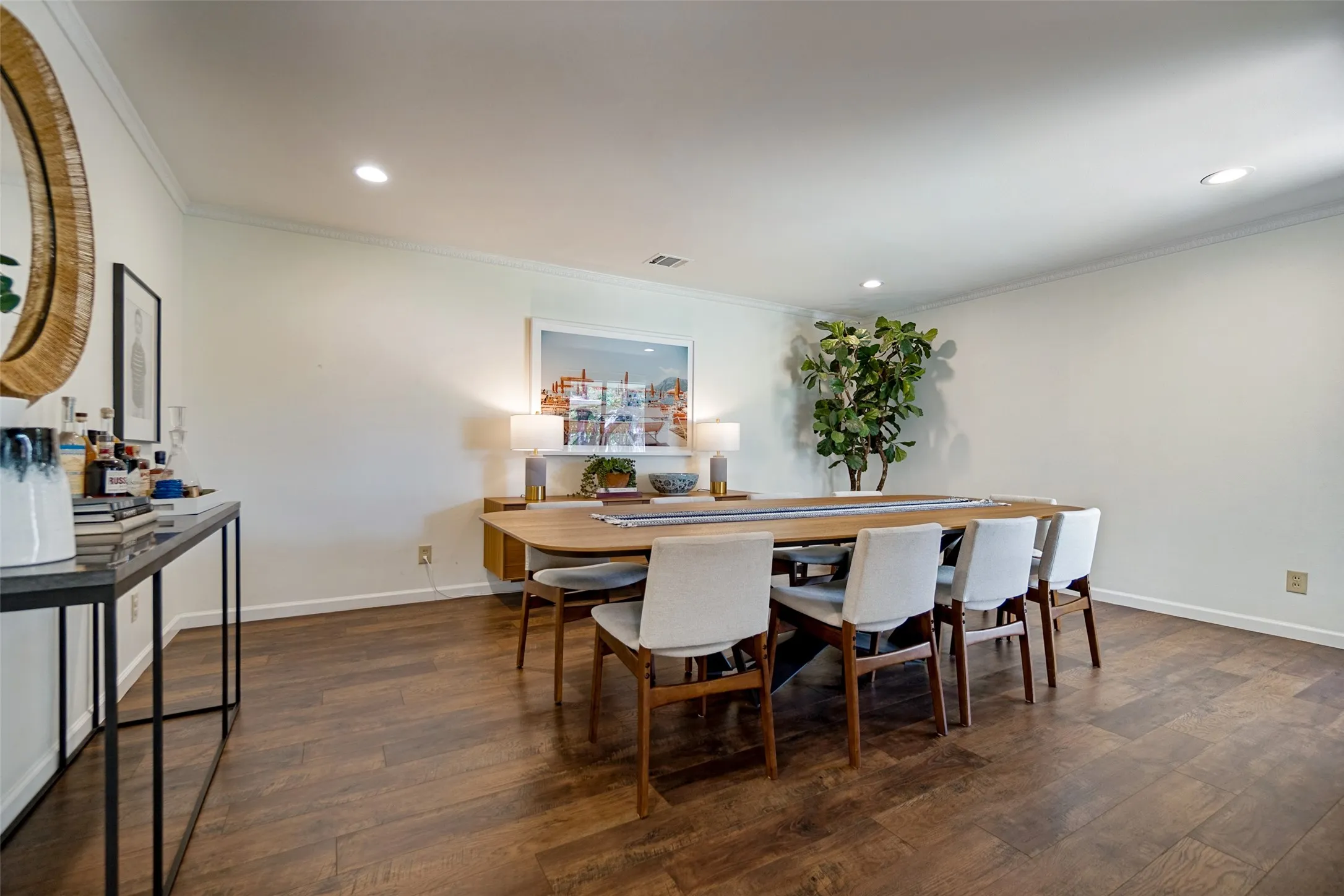Recessed lighting illuminates the wood-finish flooring and crown molding