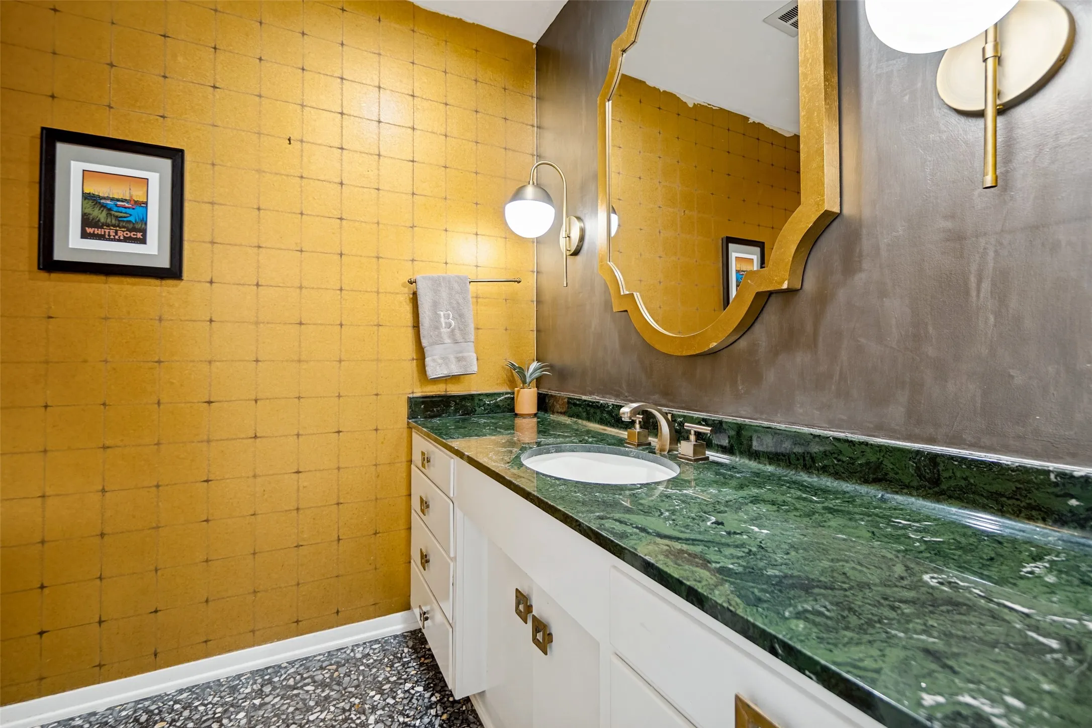 Vanity with integrated sink, green stone countertop, and brass-tone fixtures