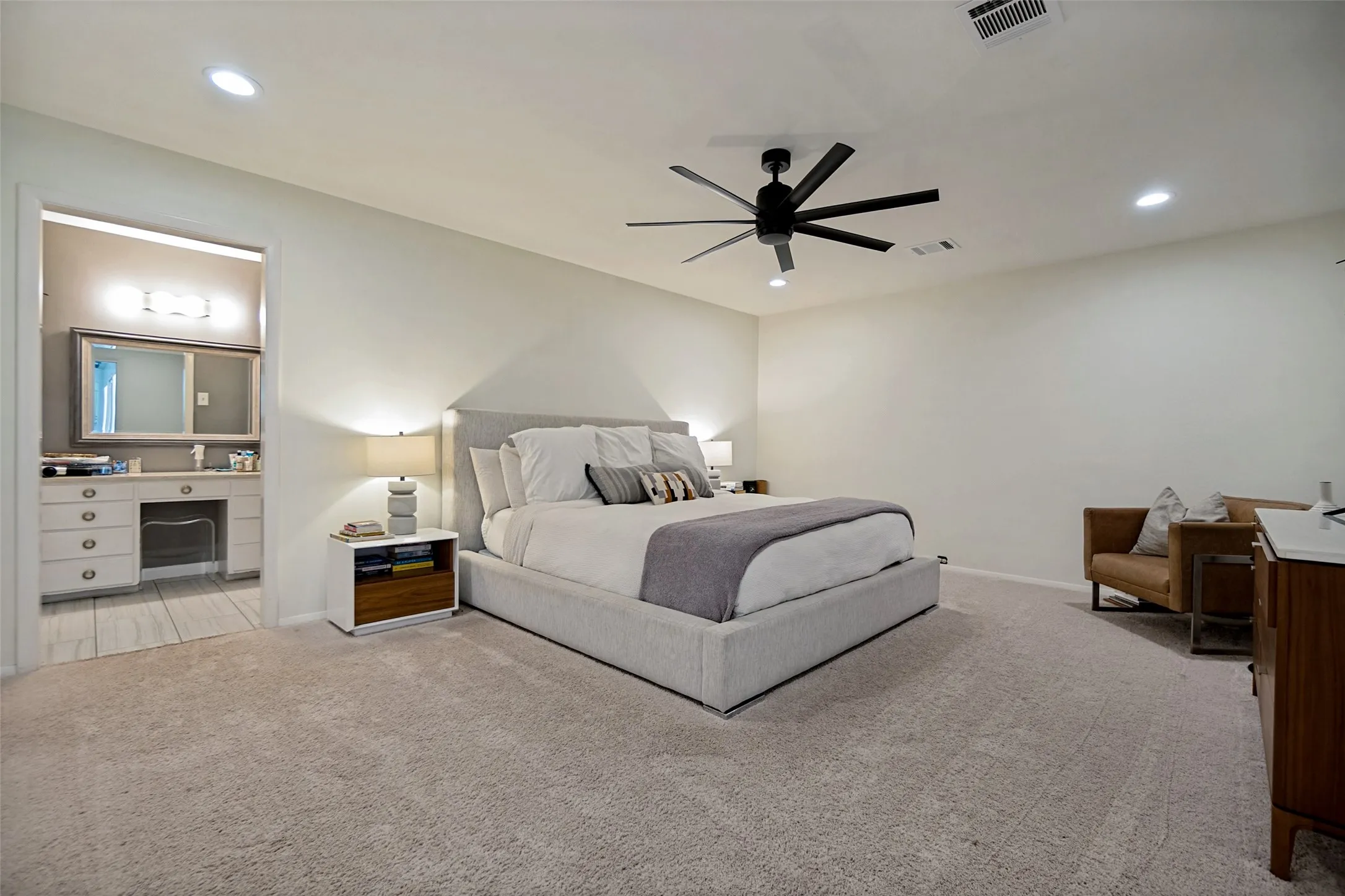 Recessed lighting, ceiling fan, plush carpeting, and a built-in vanity with mirror