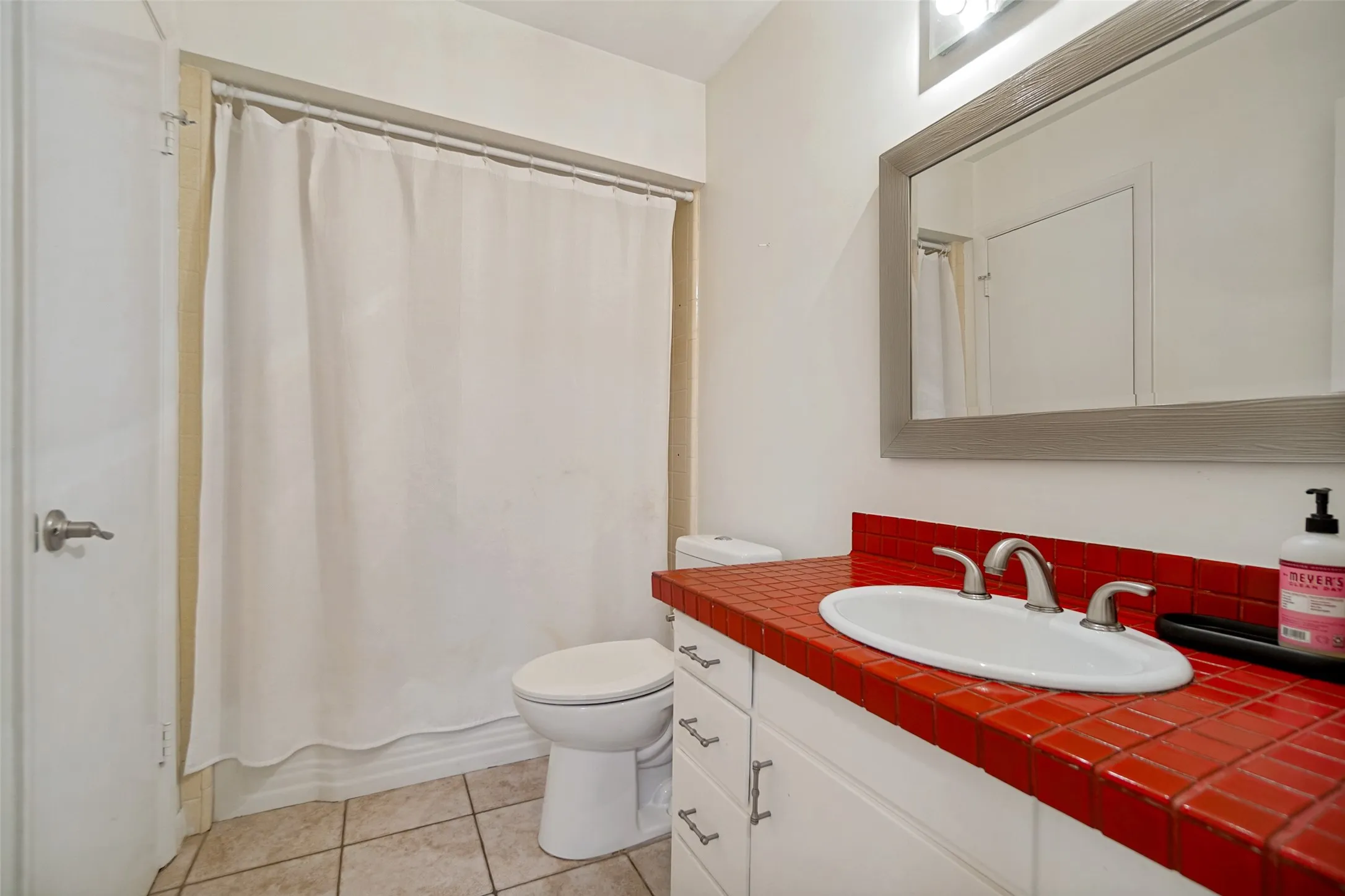 Vanity with a red tiled countertop, undermount sink, and brushed nickel fixtures
