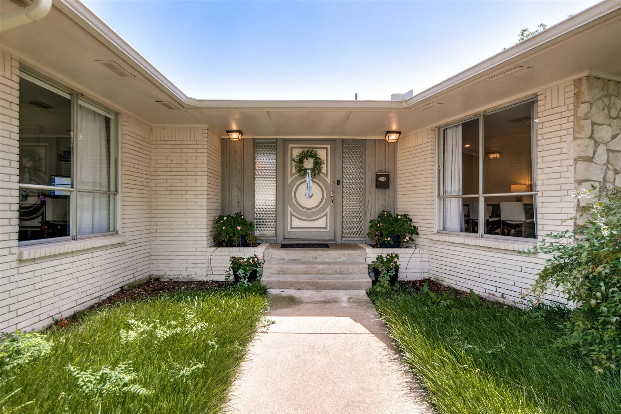 White brick exterior with stone accents, covered entry, and large windows