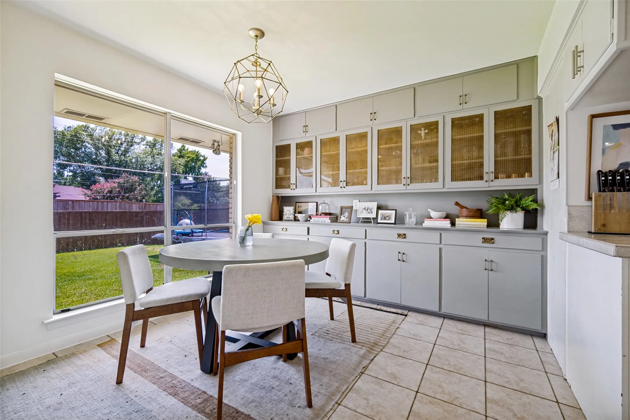 Tile flooring, expansive window, built-in cabinetry with glass-front uppers, solid surface countertop, and decorative light fixture