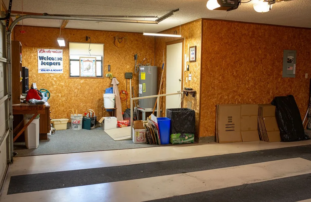 Garage with textured wall paneling, a functional window, and a built-in water heater