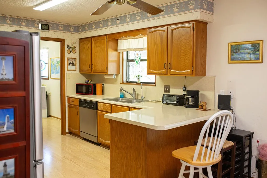 Kitchen featuring wood-finish cabinetry, light-toned countertops, and wood-finish flooring
