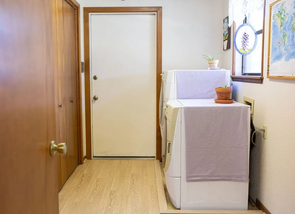 Light wood-finish flooring with a white door and wood trim